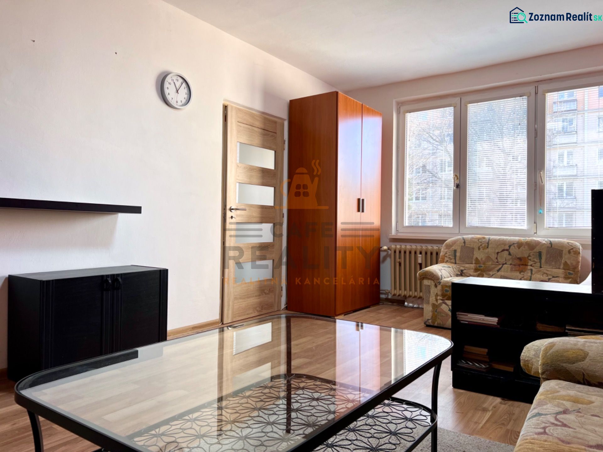 Wohnzimmer mit Sofa, Schrank und Holzboden in einer 2-Zimmer-Wohnung.