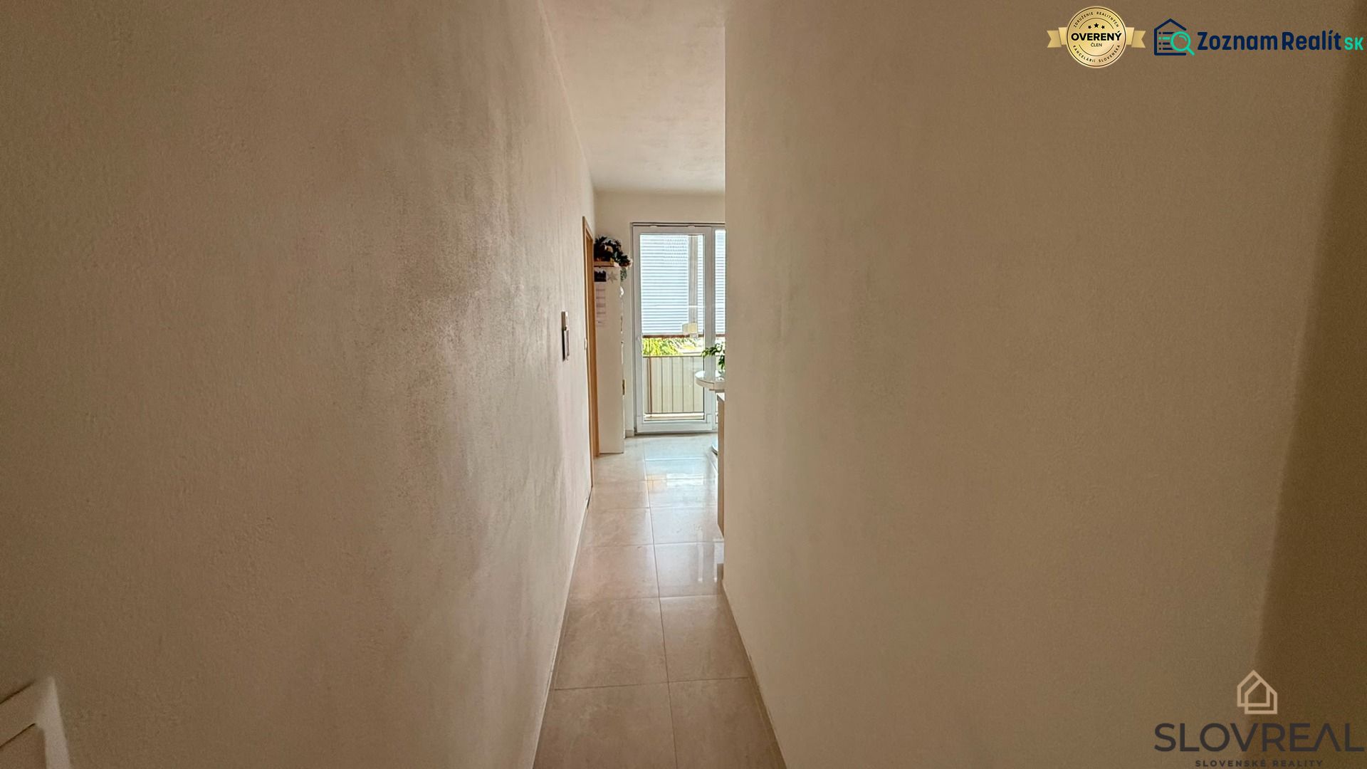 Ein enger Flur, der zu den Glastüren in einer 4-Zimmer-Wohnung führt.