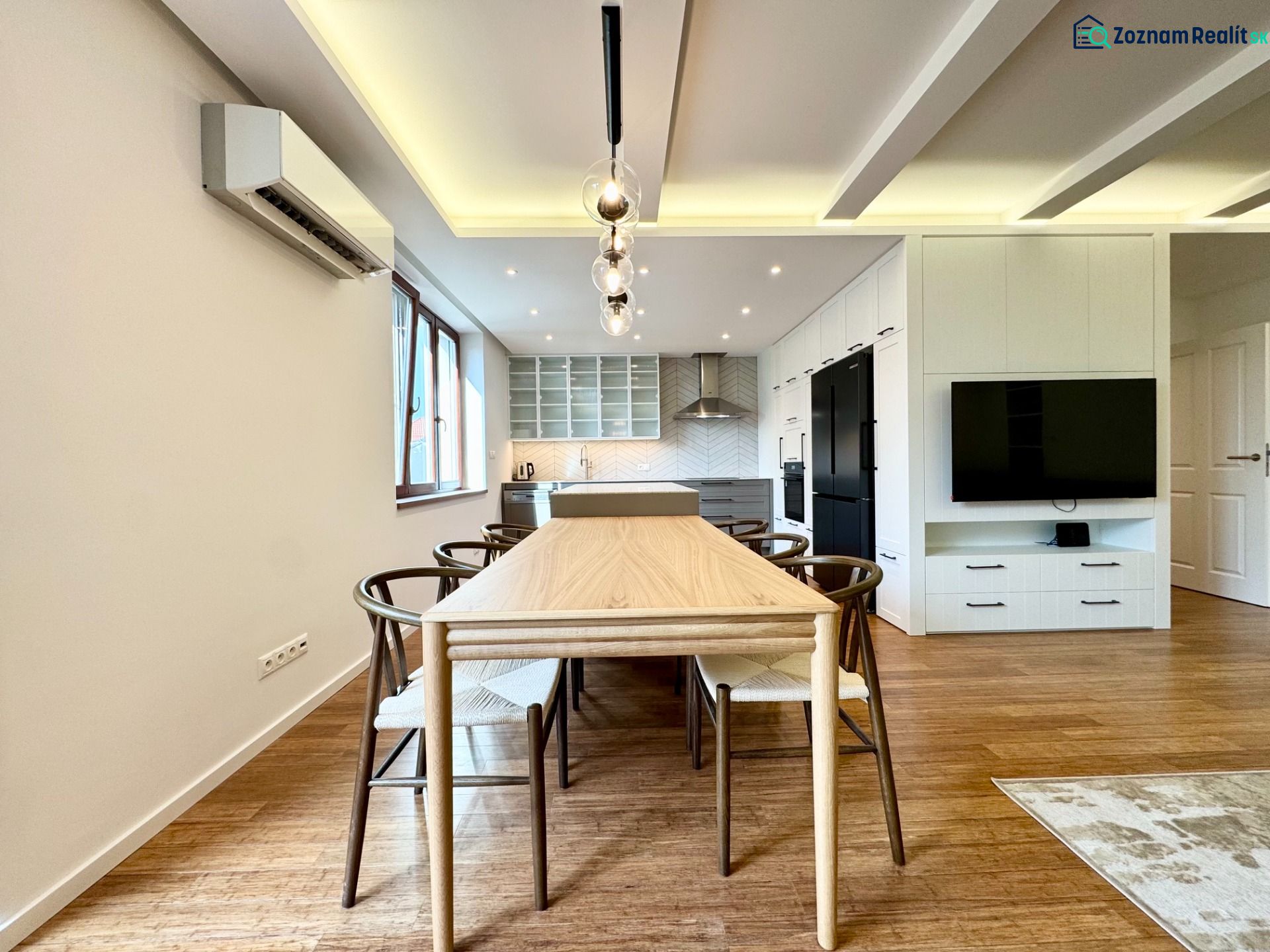 Küche in einer 3-Zimmer-Wohnung mit Beleuchtung, Holzboden und Esstisch.