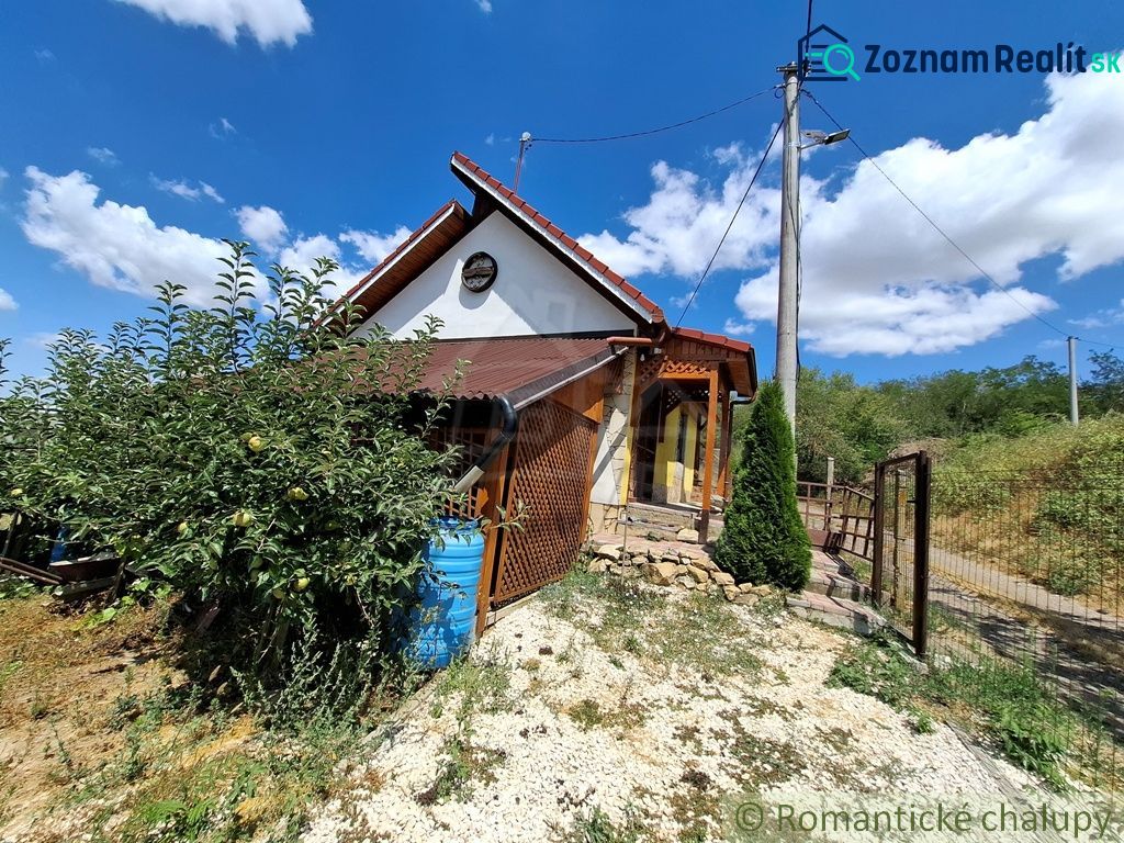 Eine Hütte in Gbelce, umgeben von Grün und Bäumen unter blauem Himmel.