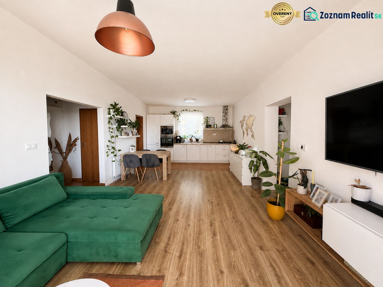 Wohnzimmer in einer 3-Zimmer-Wohnung mit Holzboden und grünem Sofa.