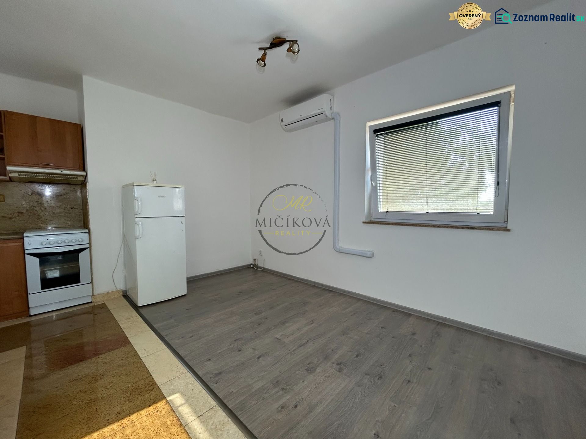 Küche in einer 2-Zimmer-Wohnung mit Holzboden, weißem Kühlschrank und Herd.