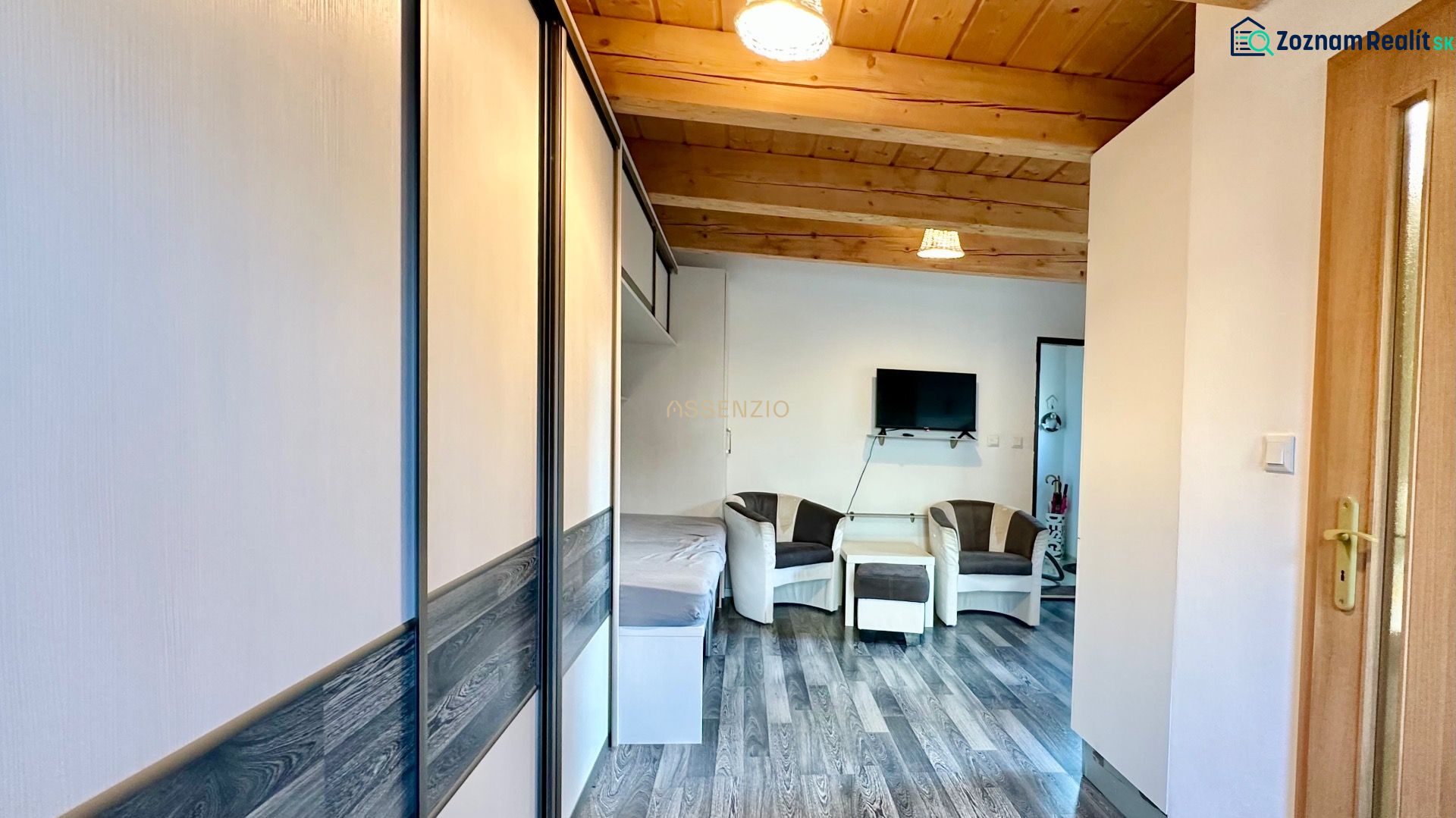 Wohnzimmer in einer 2-Zimmer-Wohnung mit Holzdecke und Boden in Holzoptik.