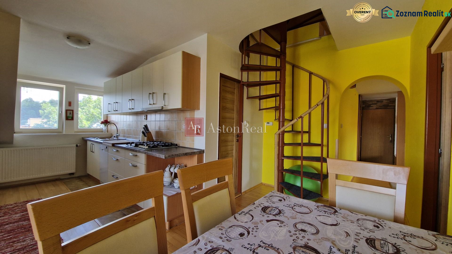 Küche in einer 2-Zimmer-Wohnung mit Wendeltreppe und hellen Schränken.