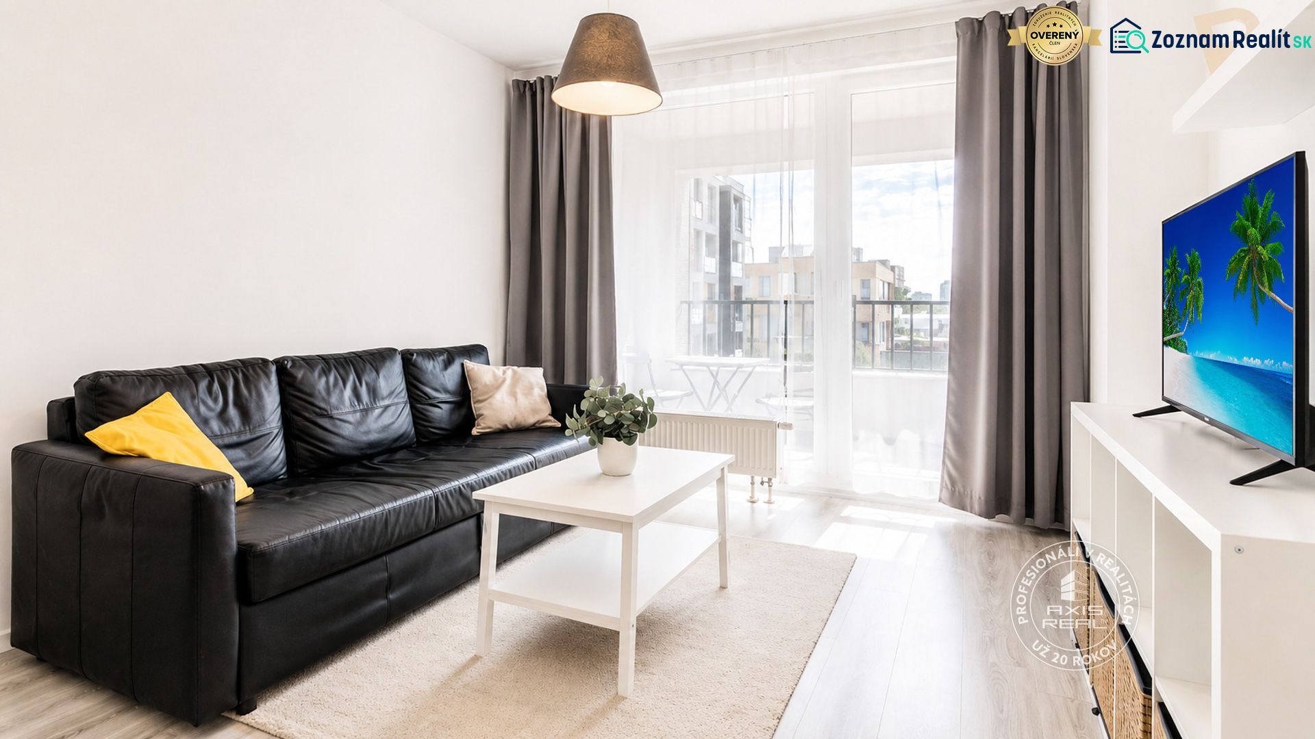 Wohnzimmer in einer 2-Zimmer-Wohnung mit schwarzem Sofa und weißem Tisch.