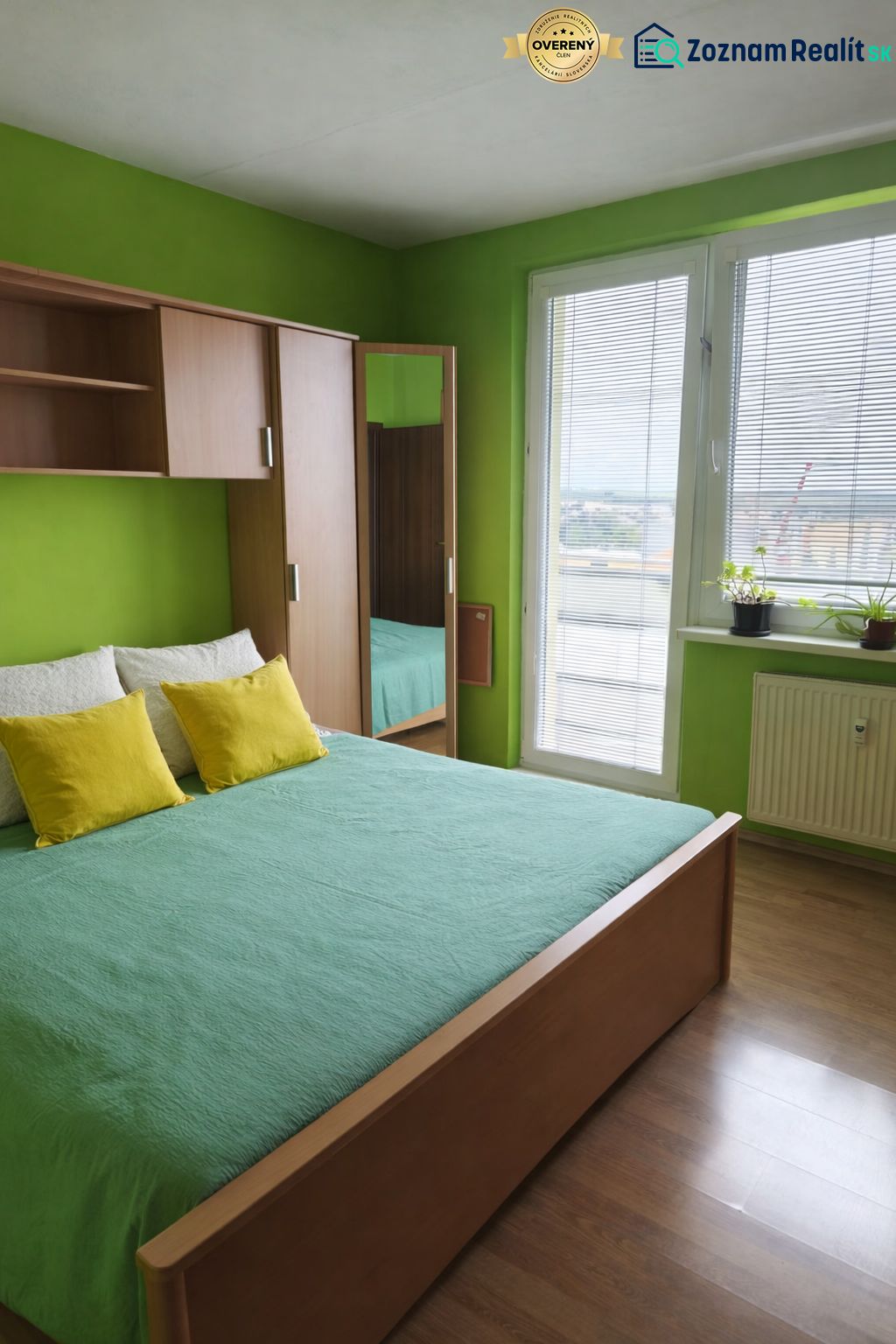 Grünes Schlafzimmer mit Bett und Schrank in Holzdekor in einer 3-Zimmer-Wohnung.