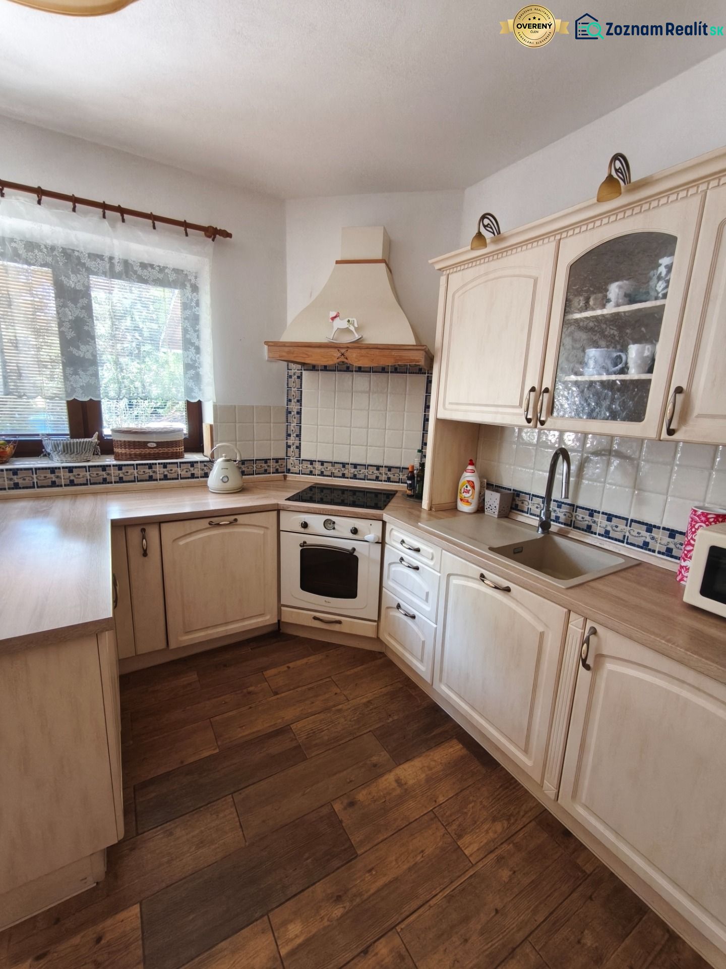 Küche mit Holzdekorboden, weißen Schränken und Fliesen in einem Einfamilienhaus.