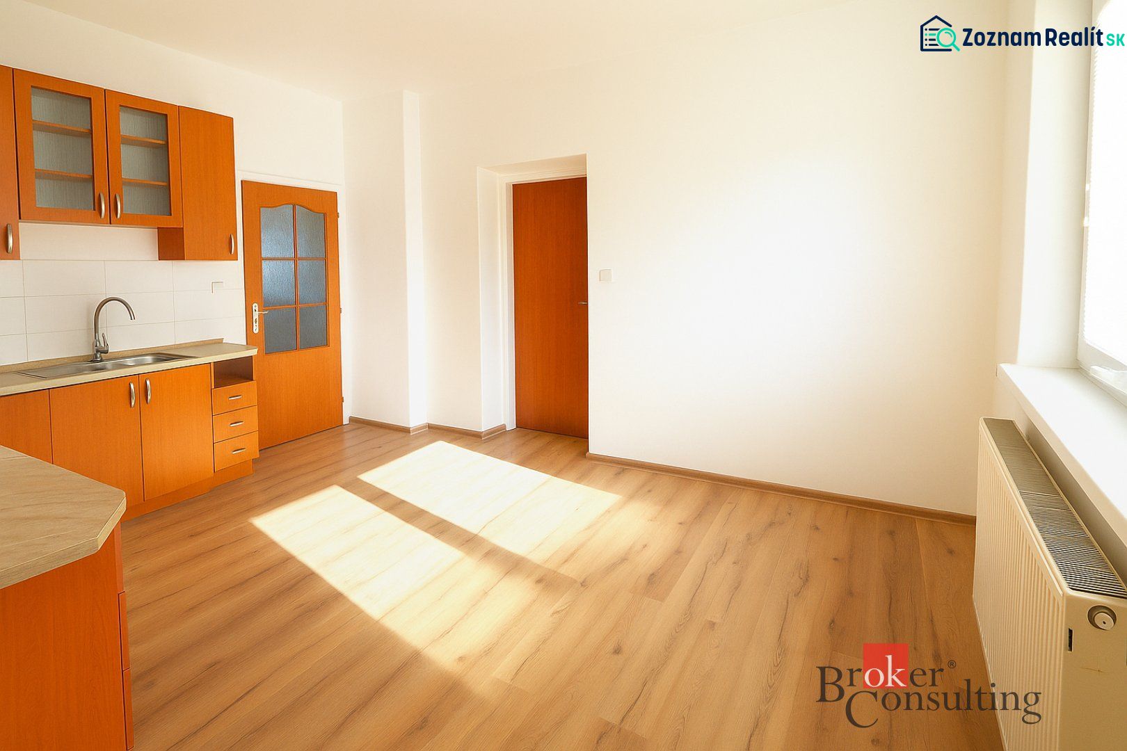 Küche in einer 2-Zimmer-Wohnung mit orangefarbener Küchenzeile und Boden in Holzoptik.