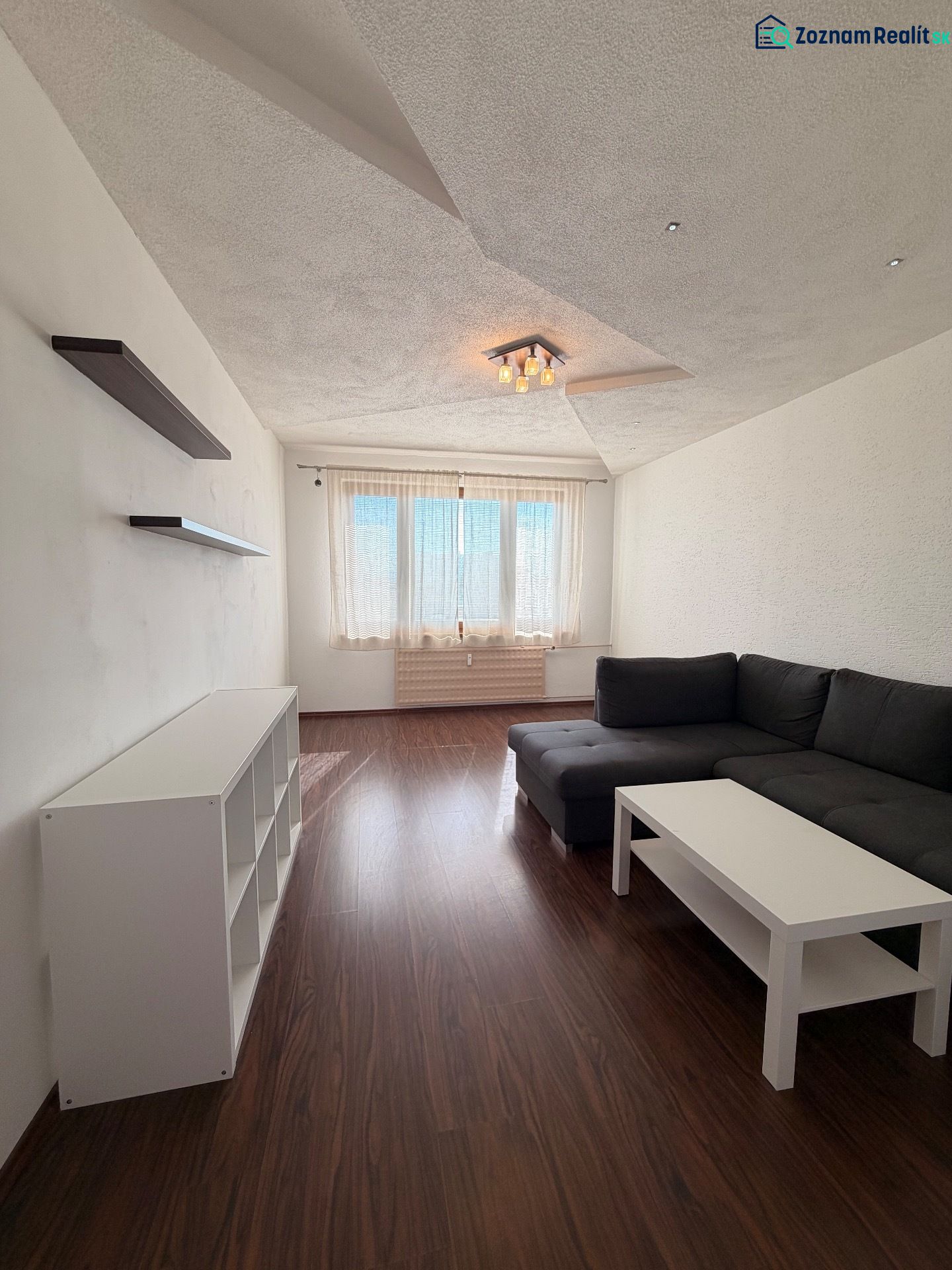 Wohnzimmer in einer 3-Zimmer-Wohnung mit Holzboden und Ecksofa.