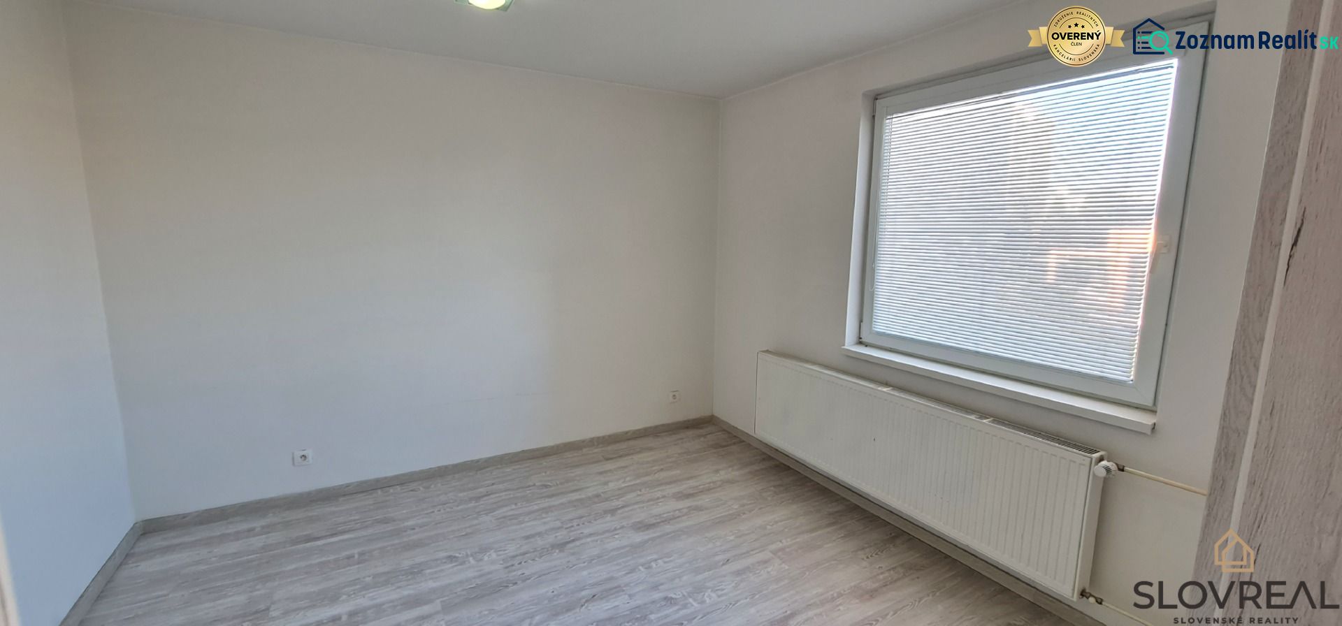 Ein Zimmer in einer 2-Zimmer-Wohnung mit weißen Wänden und einem Boden in Holzoptik.