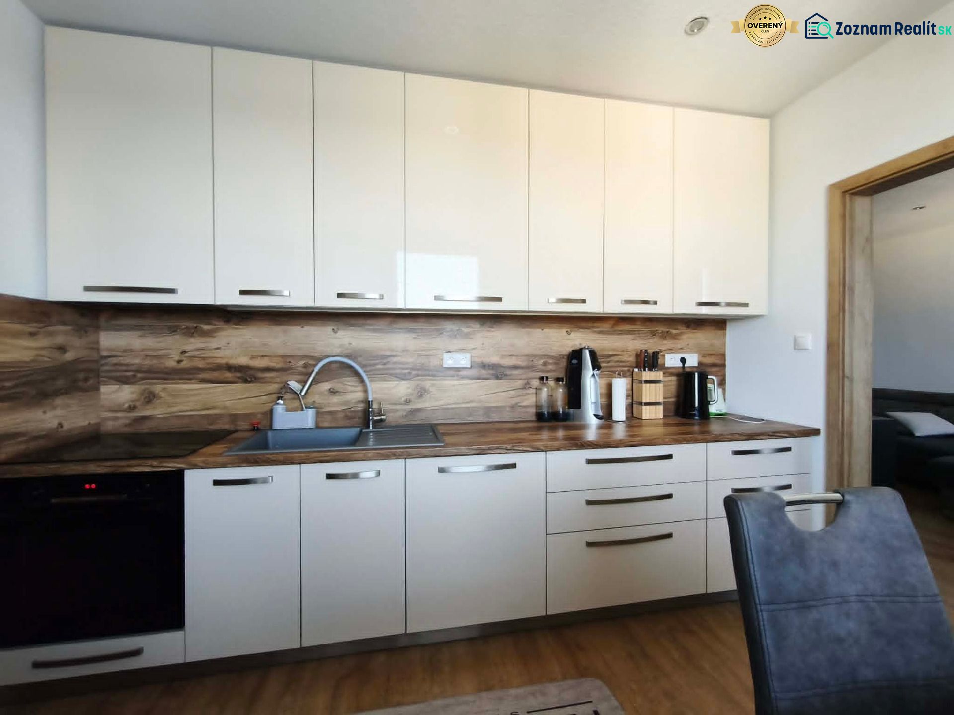 Küche in einer 3-Zimmer-Wohnung mit weißen Schränken und Holzboden.