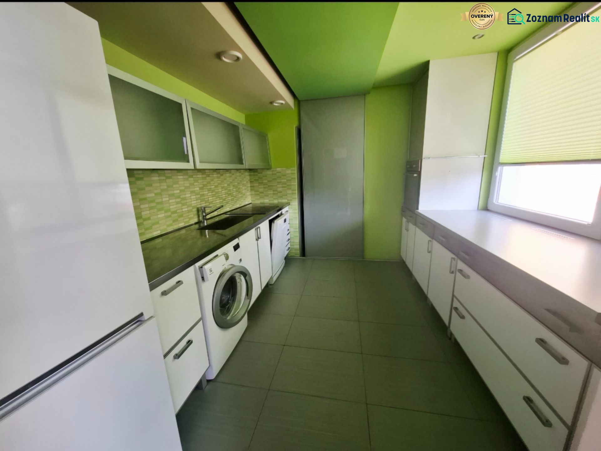 Küche in einer 3-Zimmer-Wohnung mit Waschmaschine, weißen Möbeln und grünen Wänden.