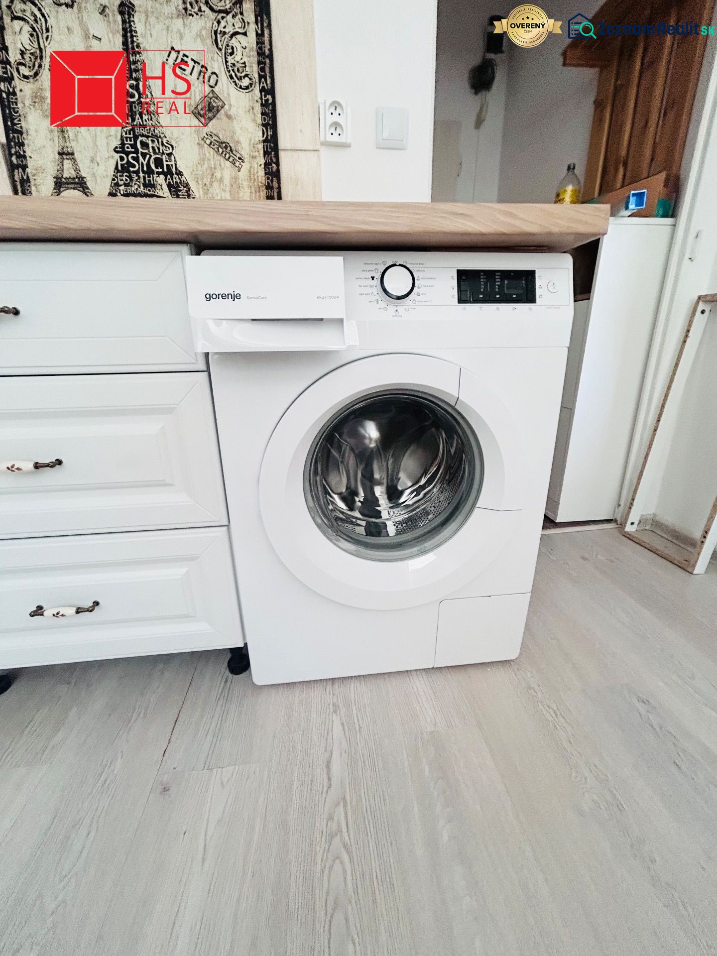 Waschmaschine in der Küche eines Einzimmerapartments mit Holzboden und Holzarbeitsplatte.