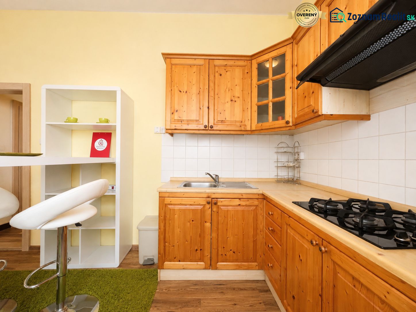 Küche in einer Einzimmerwohnung mit Holzschränken und Boden in Holzoptik.