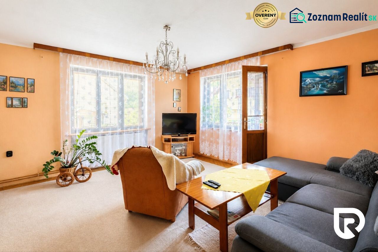 Wohnzimmer mit cremefarbenen Wänden, einem orangefarbenen Sessel und einem grauen Sofa in einem Einfamilienhaus.