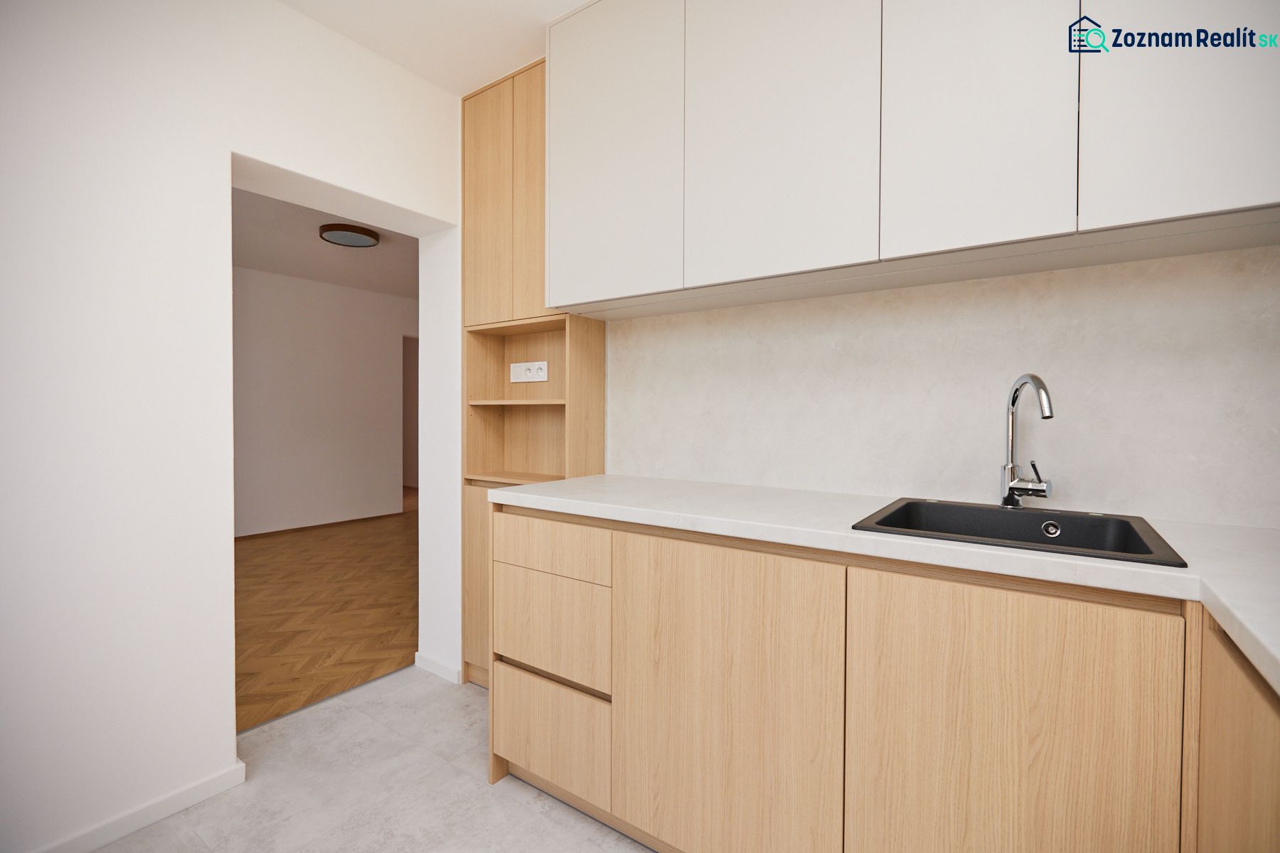 Eine Küchenzeile mit hellen Schränken und einem Boden in Holzoptik, 3-Zimmer-Wohnung.