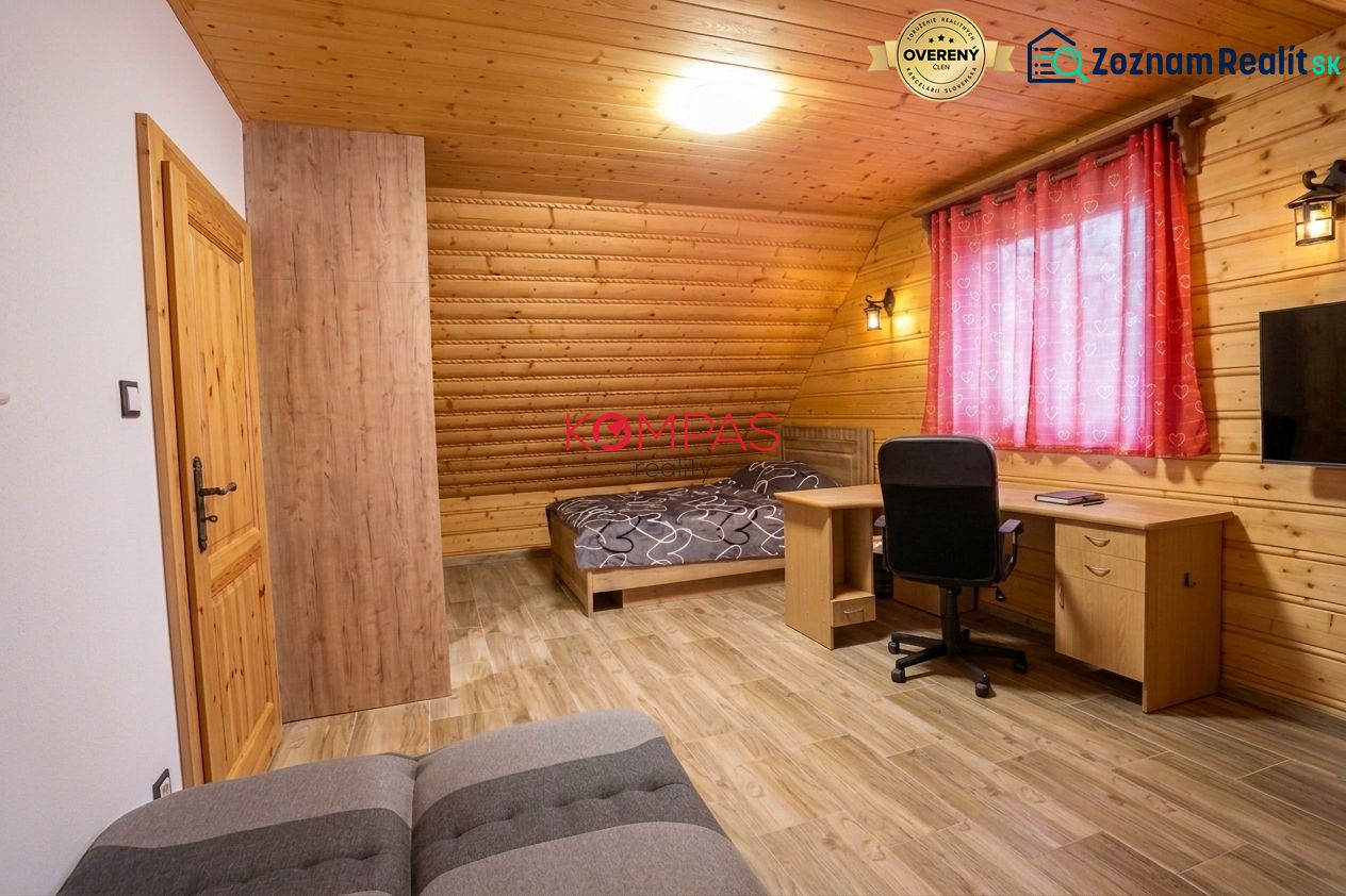 Ein Zimmer in einem Einfamilienhaus mit Holzwänden, einem Boden mit Holzdekor und einem Schreibtisch.