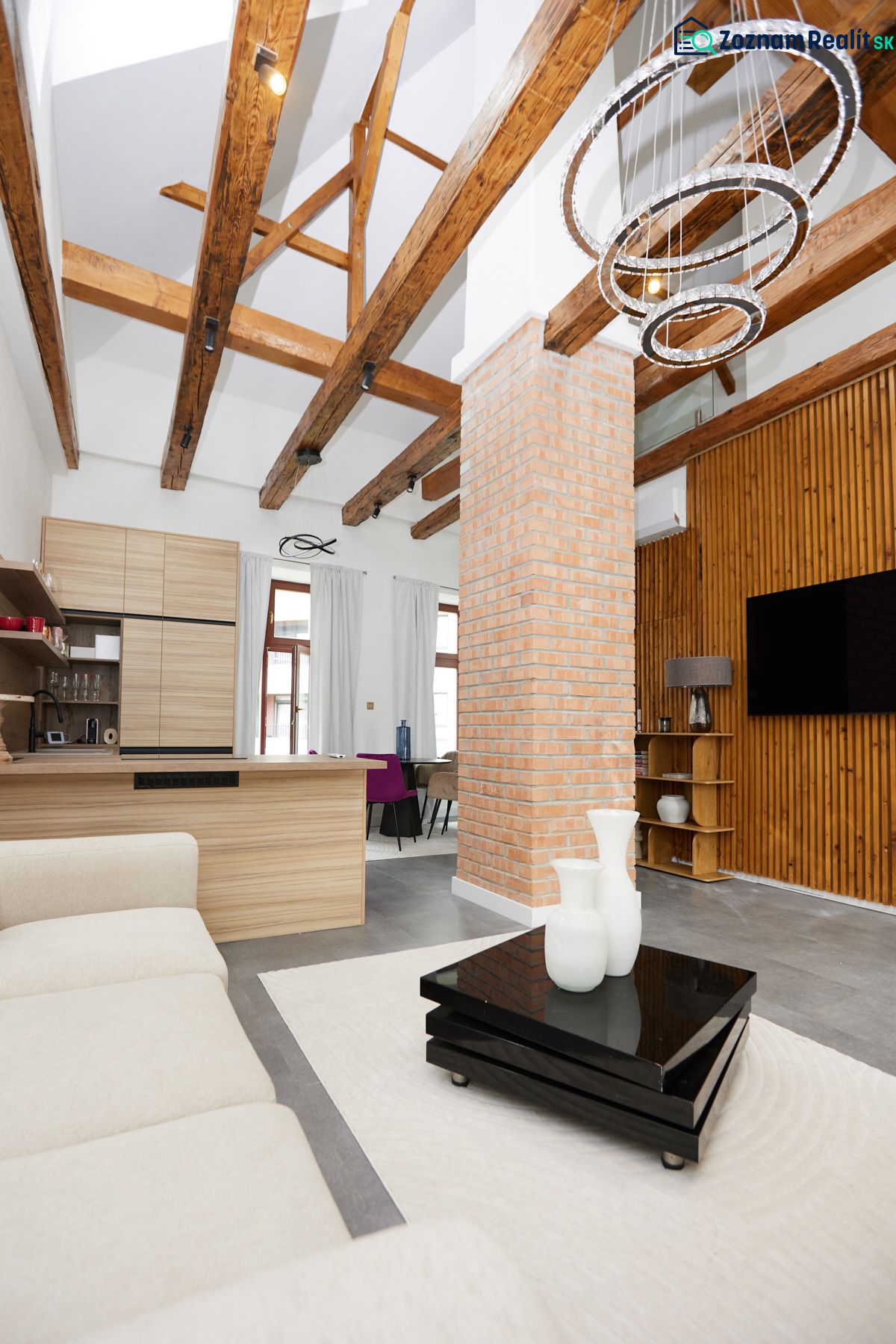 Wohnzimmer in einer 3-Zimmer-Wohnung mit sichtbaren Balken und einer Ziegelsteinsäule.