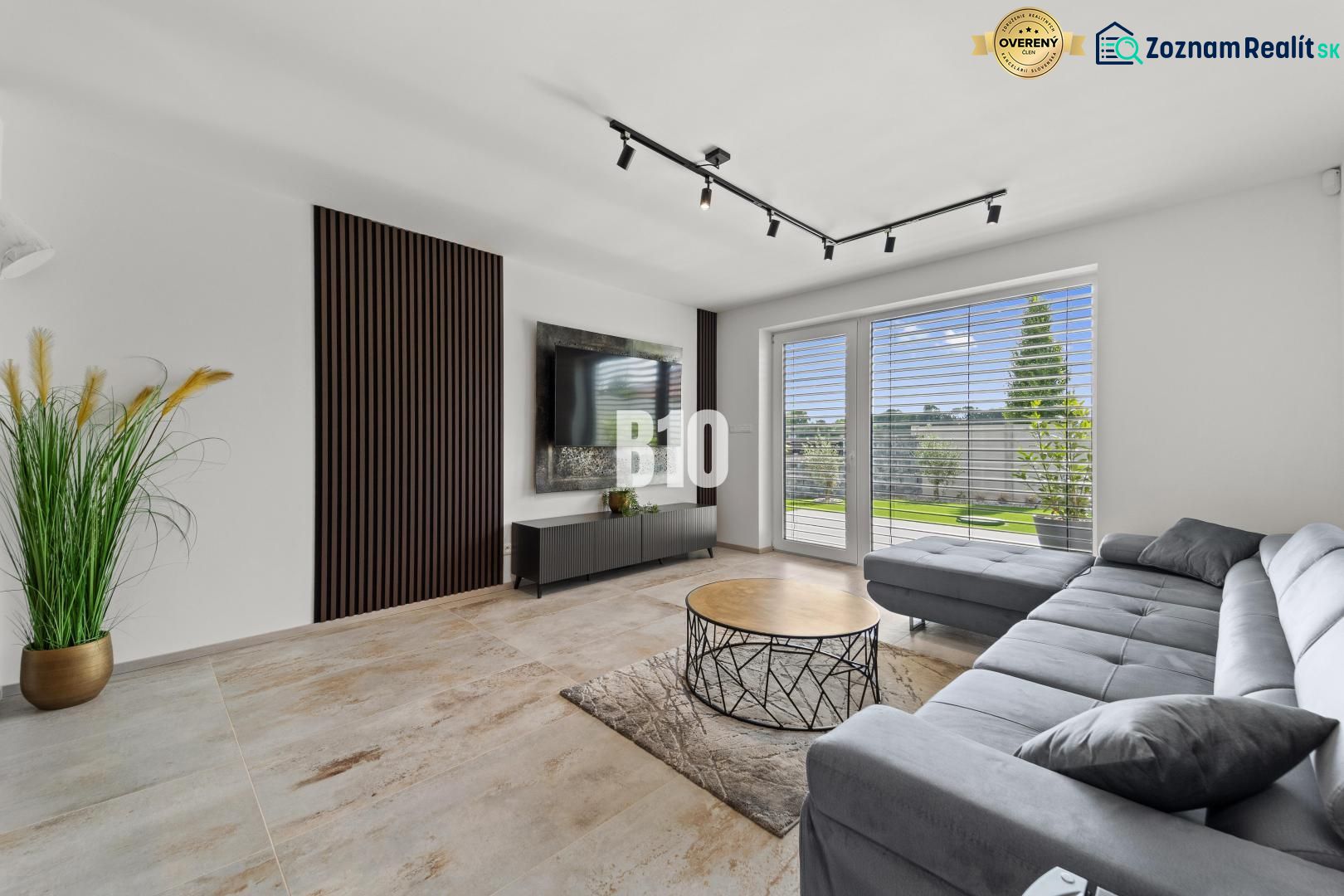 Wohnzimmer in einem Einfamilienhaus mit Sofa, Fernseher und Fenster mit Ausblick.