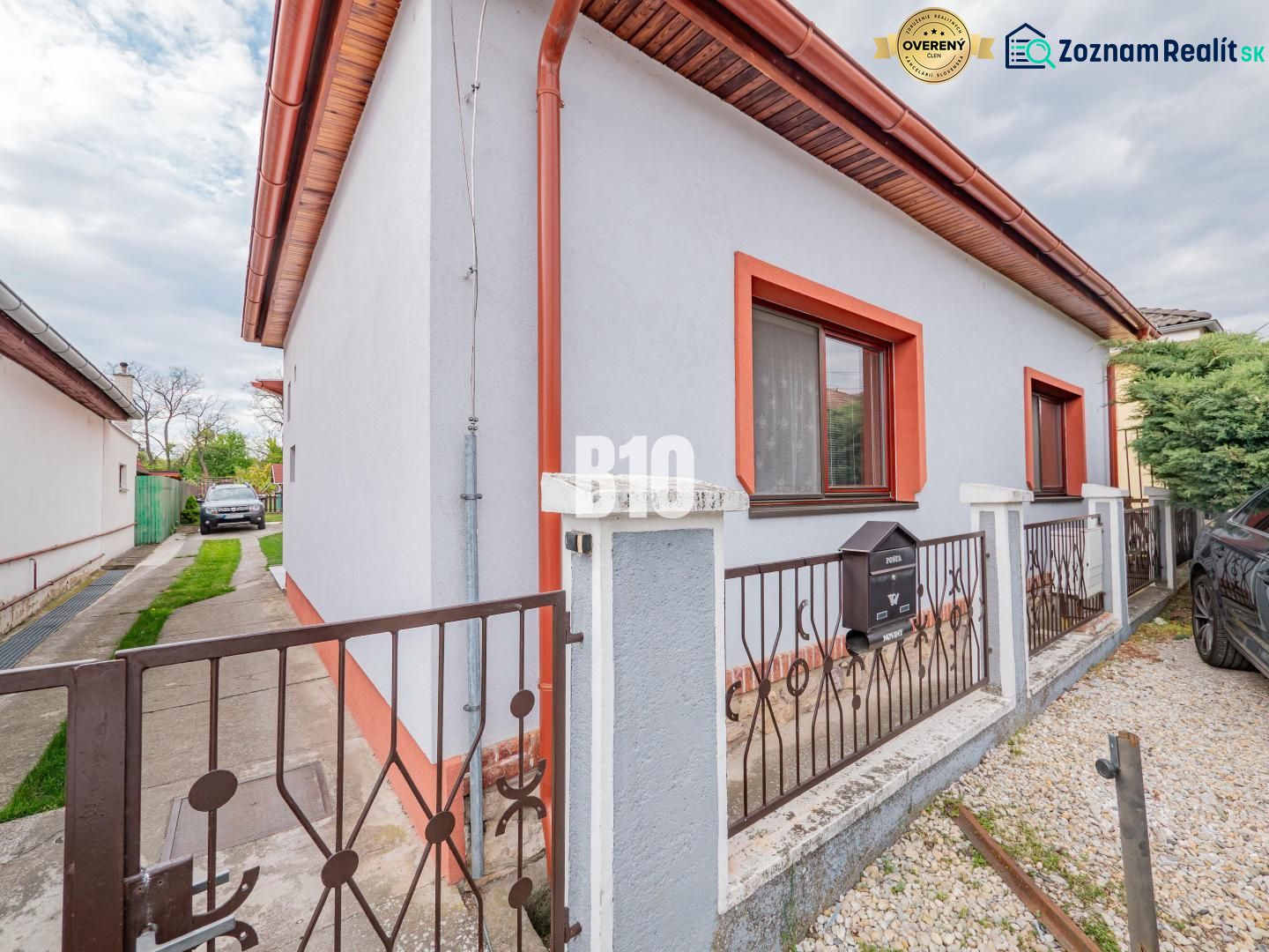 Ein Einfamilienhaus in Nitra mit weißer Fassade, roter Umrandung und einem Garten.