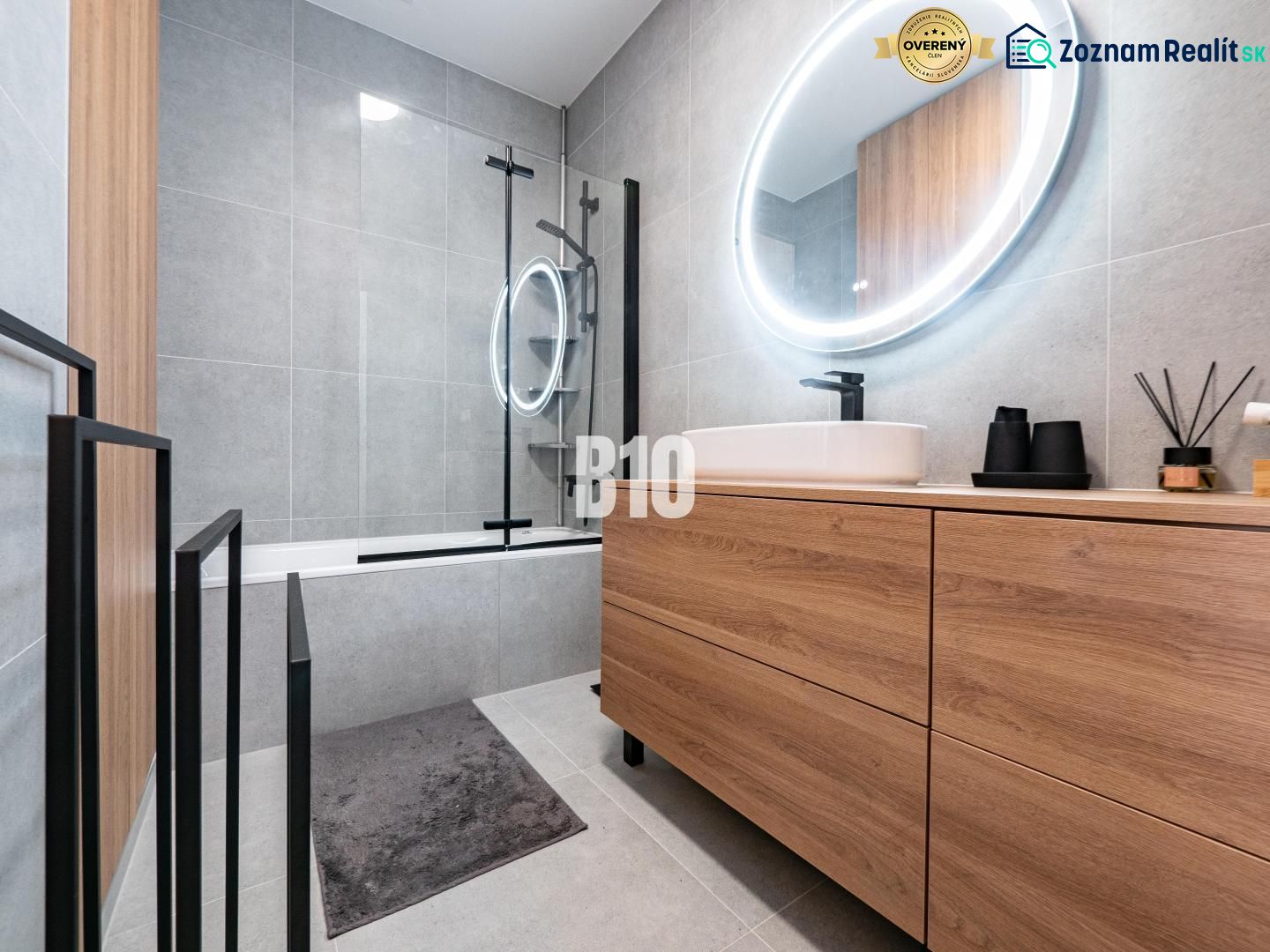 Badezimmer mit Holzdekor in einem Einfamilienhaus, mit Badewanne und ovalem Spiegel mit Beleuchtung.