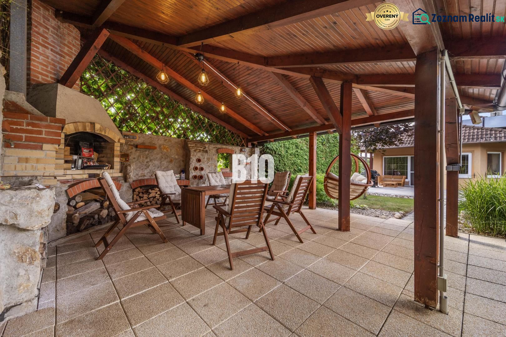Überdachte Terrasse mit Kamin und Holzstühlen bei einem Einfamilienhaus in Nitra.