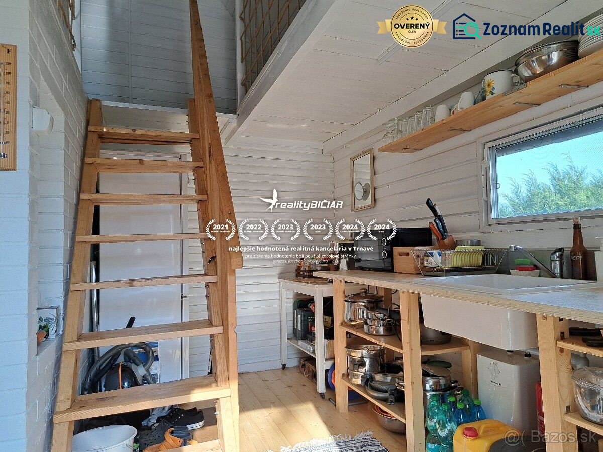 Innenraum einer Hütte mit Treppe, Küche und Boden in Holzoptik.