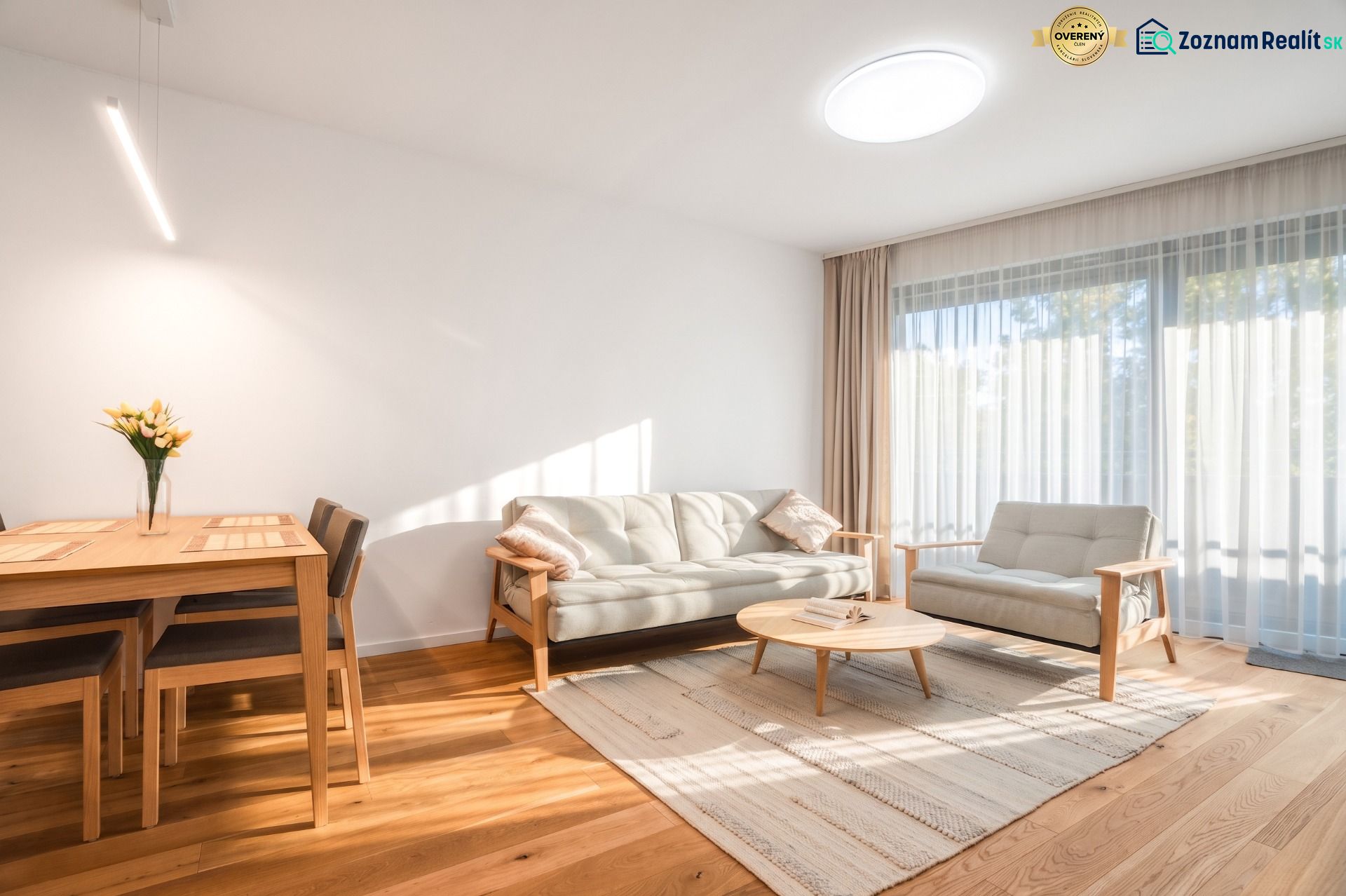 Helles Wohnzimmer mit Holzboden, Sofa und Esstisch.