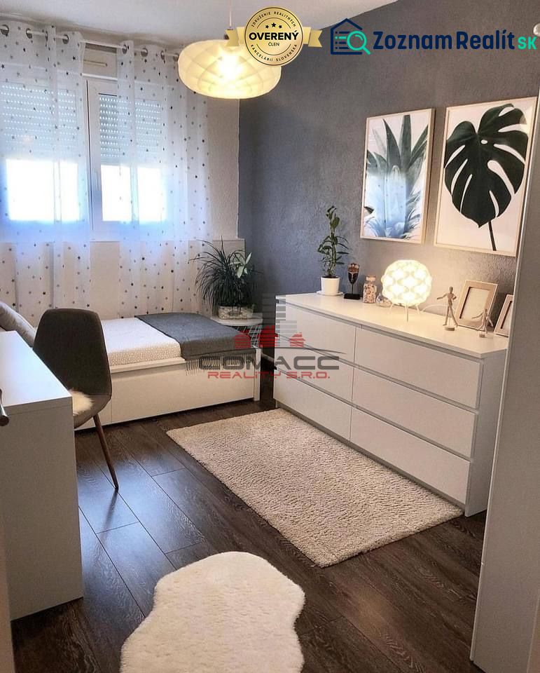 Ein Zimmer in einem Einfamilienhaus mit einem Boden in Holzoptik, Kunstgemälden und dekorativen Blumen.