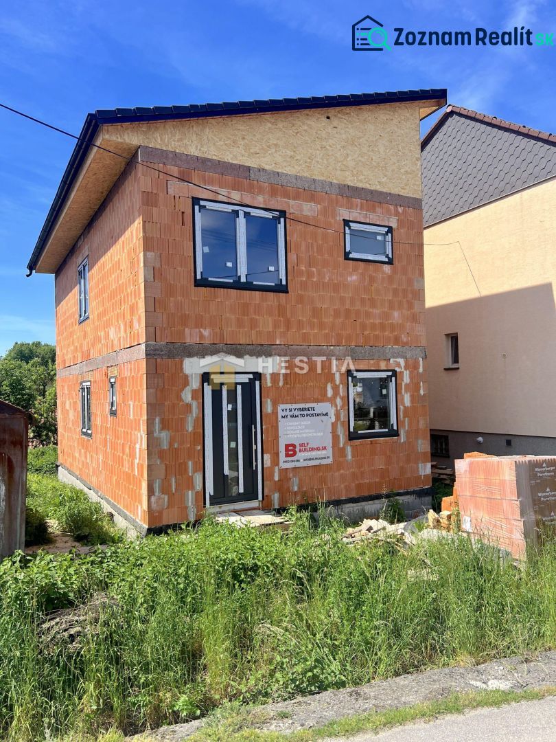 Unvollendetes Einfamilienhaus in Cerová mit sichtbaren Ziegelwänden und Kunststofffenstern.