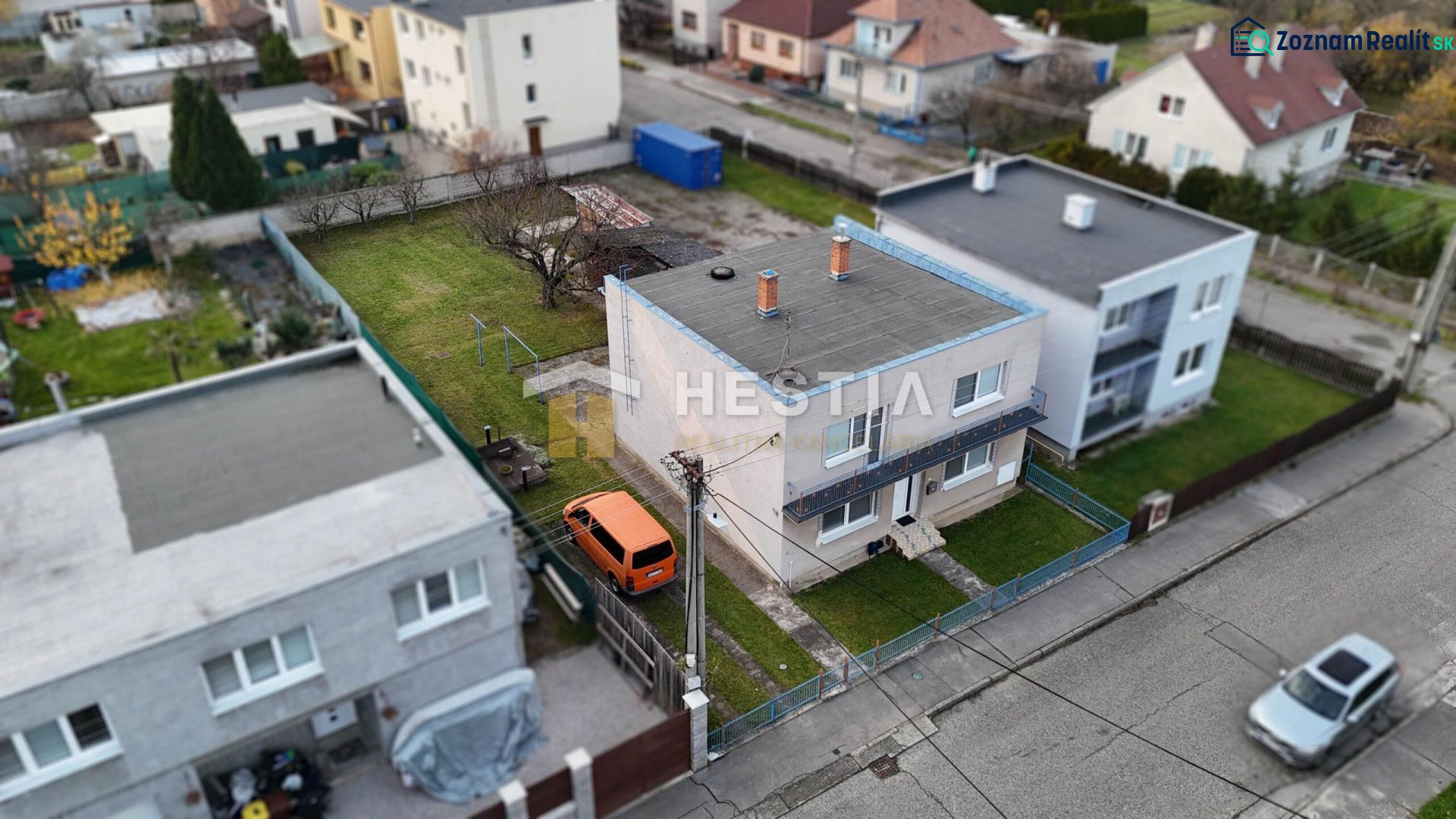 Ein Einfamilienhaus in Senica mit einem eingezäunten Hof und einem geparkten orangefarbenen Auto.