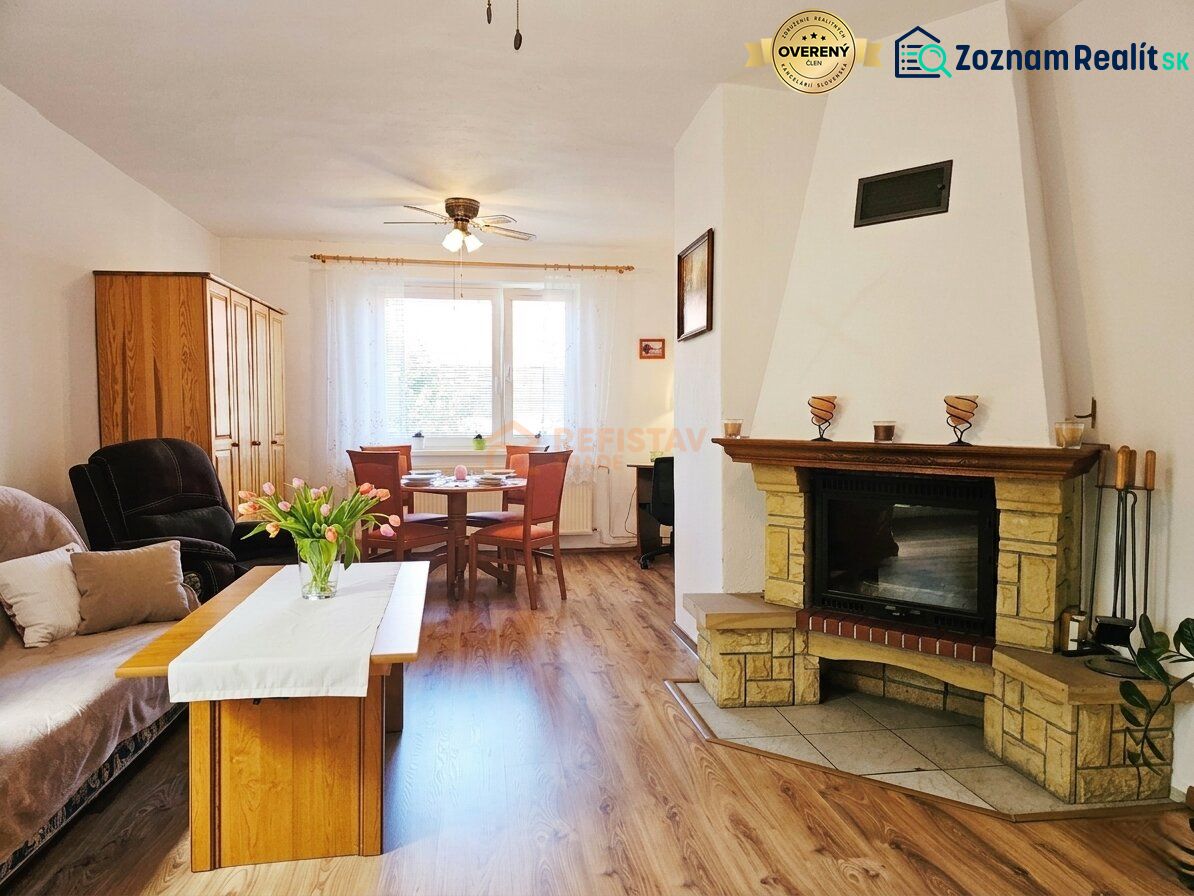 Ein Zimmer eines Einfamilienhauses mit Kamin, Sitzgarnitur und einem Boden mit Holzdekor.