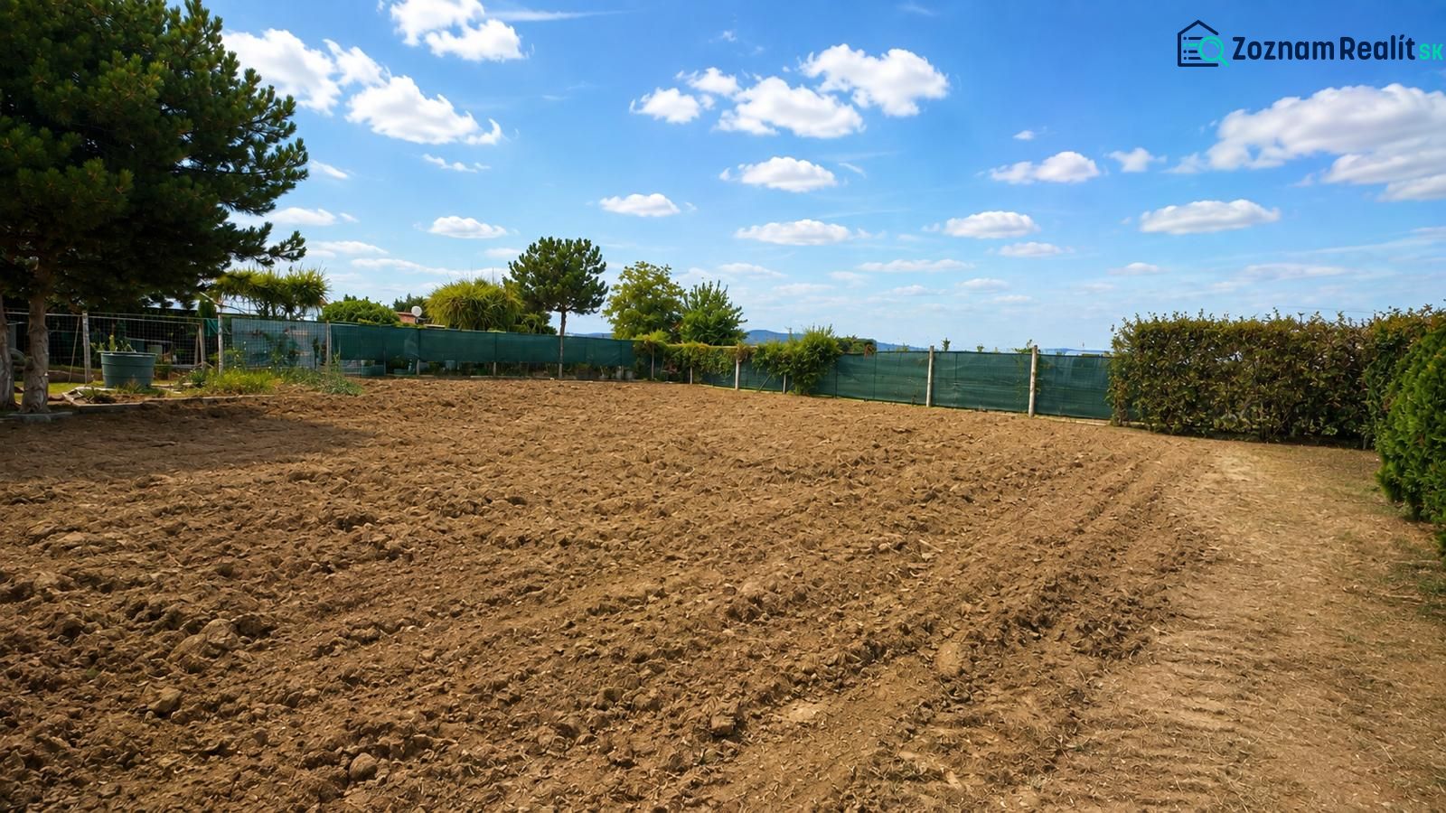 Baugrundstücke in Pravotice mit bewirtschaftetem Boden, grüner Hecke und blauem Himmel.