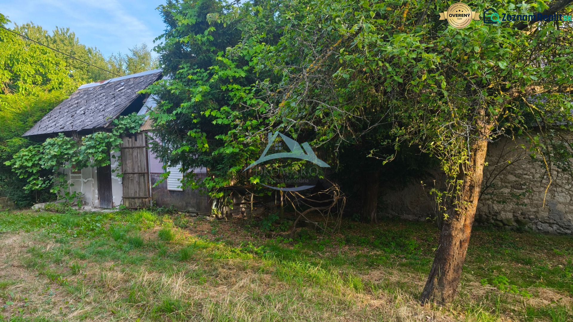 Ein Einfamilienhaus in Čelovce, umgeben von Grün und Bäumen, mit einem älteren Unterstand.
