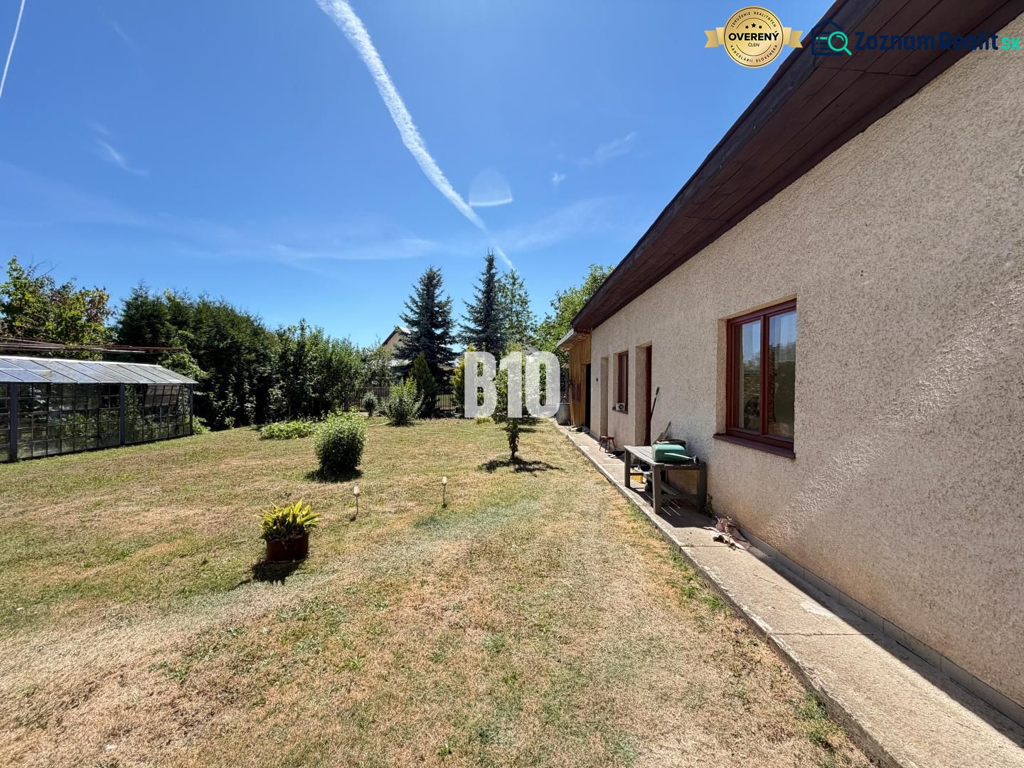 Ein Einfamilienhaus in Kláštor pod Znievom mit Garten und Gewächshaus an einem sonnigen Tag.
