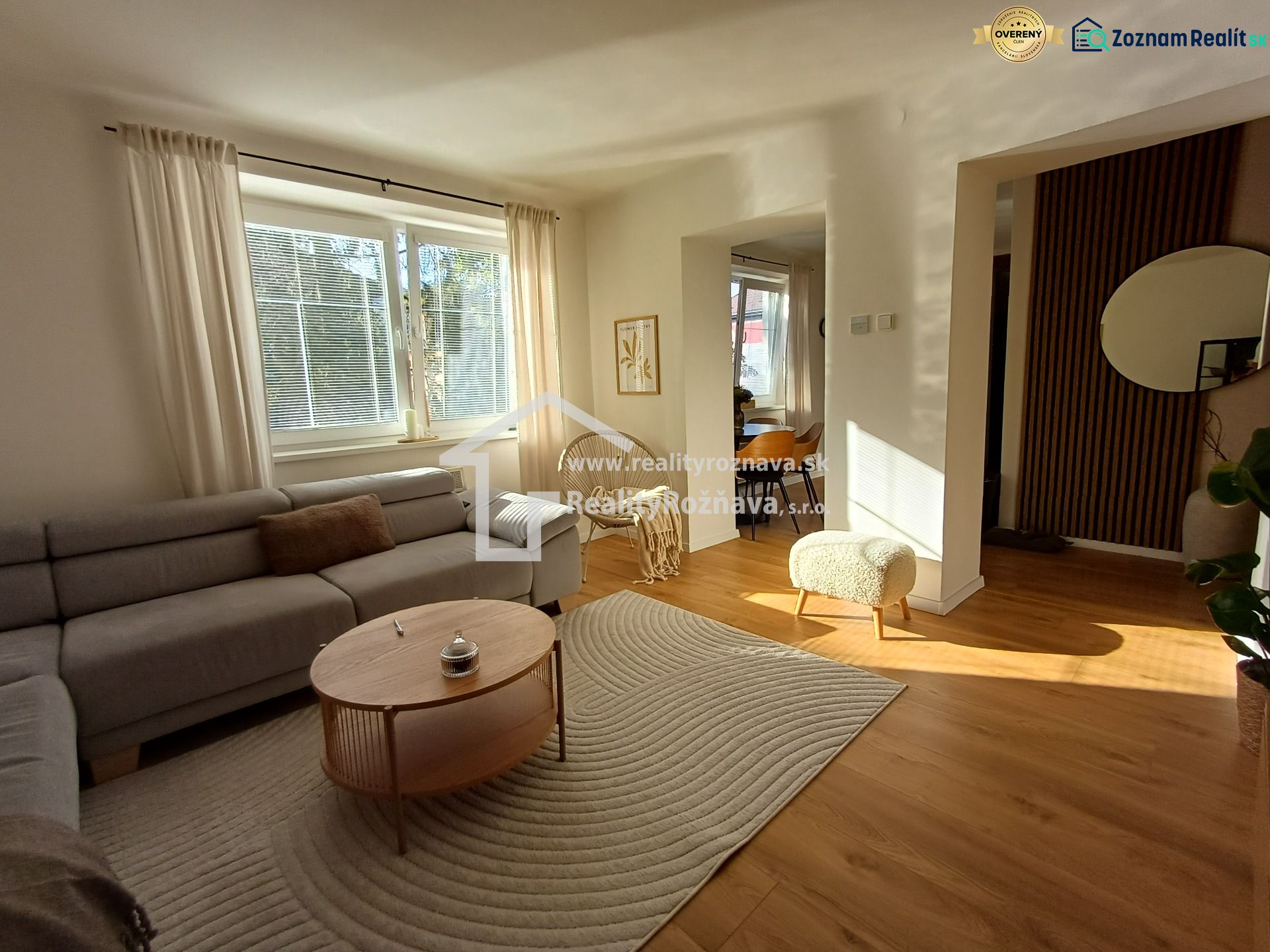 Wohnzimmer in einer Zweizimmerwohnung mit einem bequemen Sofa und einem Boden in Holzoptik.