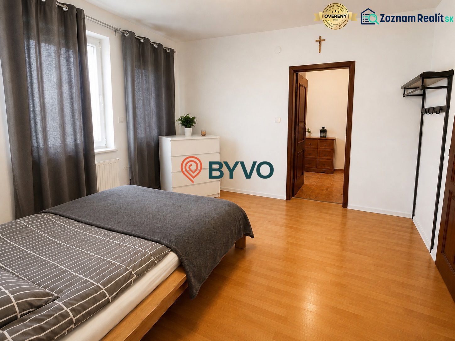 Schlafzimmer im Einfamilienhaus mit Bett, Kommode und Boden in Holzoptik.