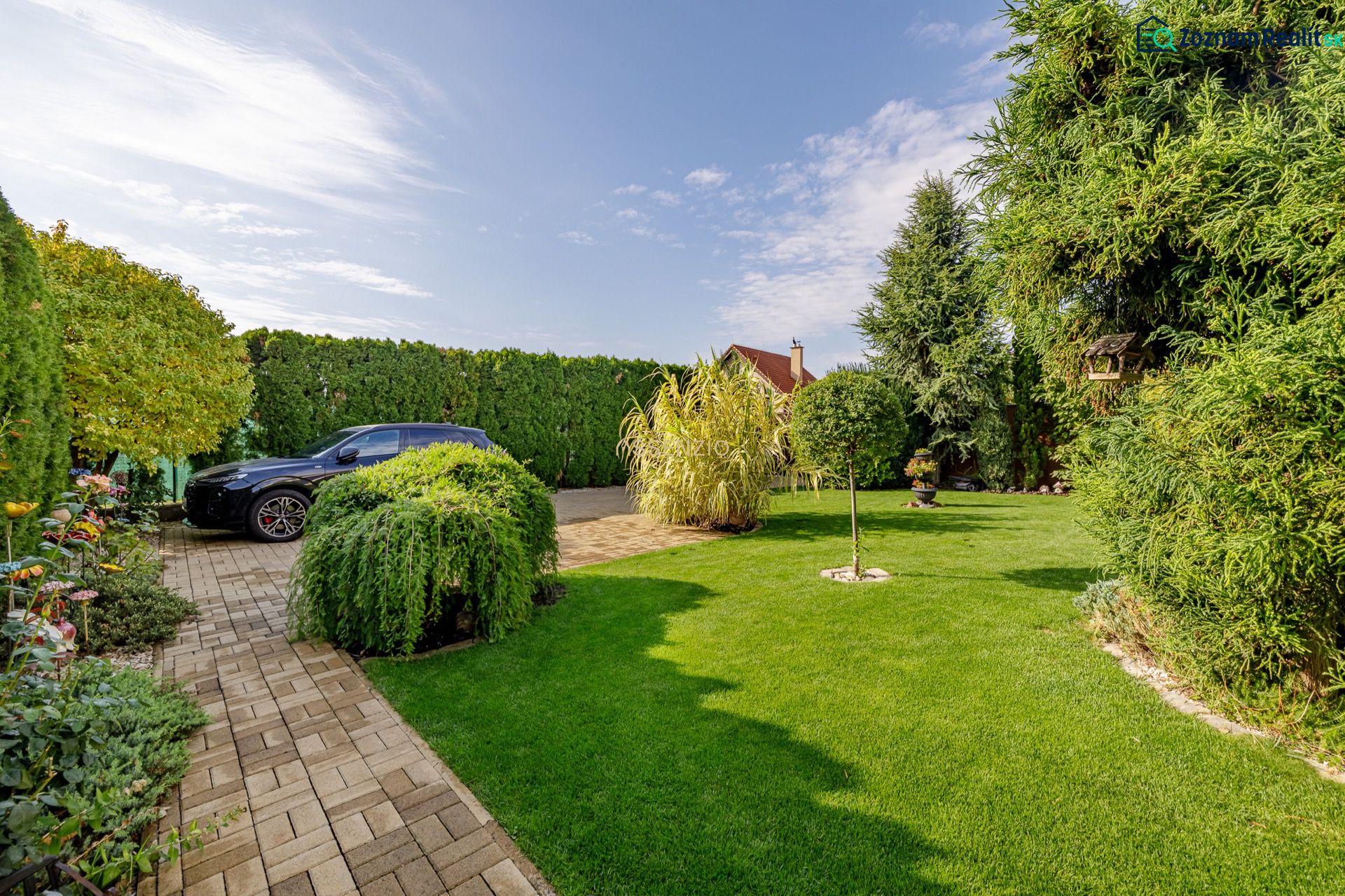 Garten bei einem Einfamilienhaus in der Majerská-Straße in Nová Dedinka. Elegantes Grün und Auto.
