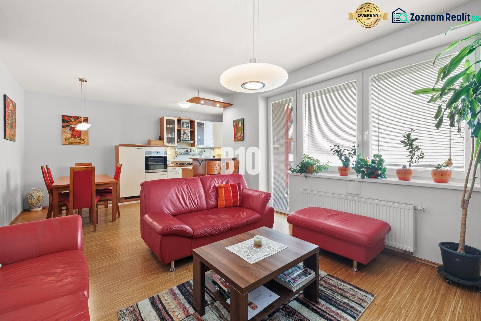 Wohnzimmer in einer 4-Zimmer-Wohnung mit roten Sofas und einem Boden in Holzoptik.