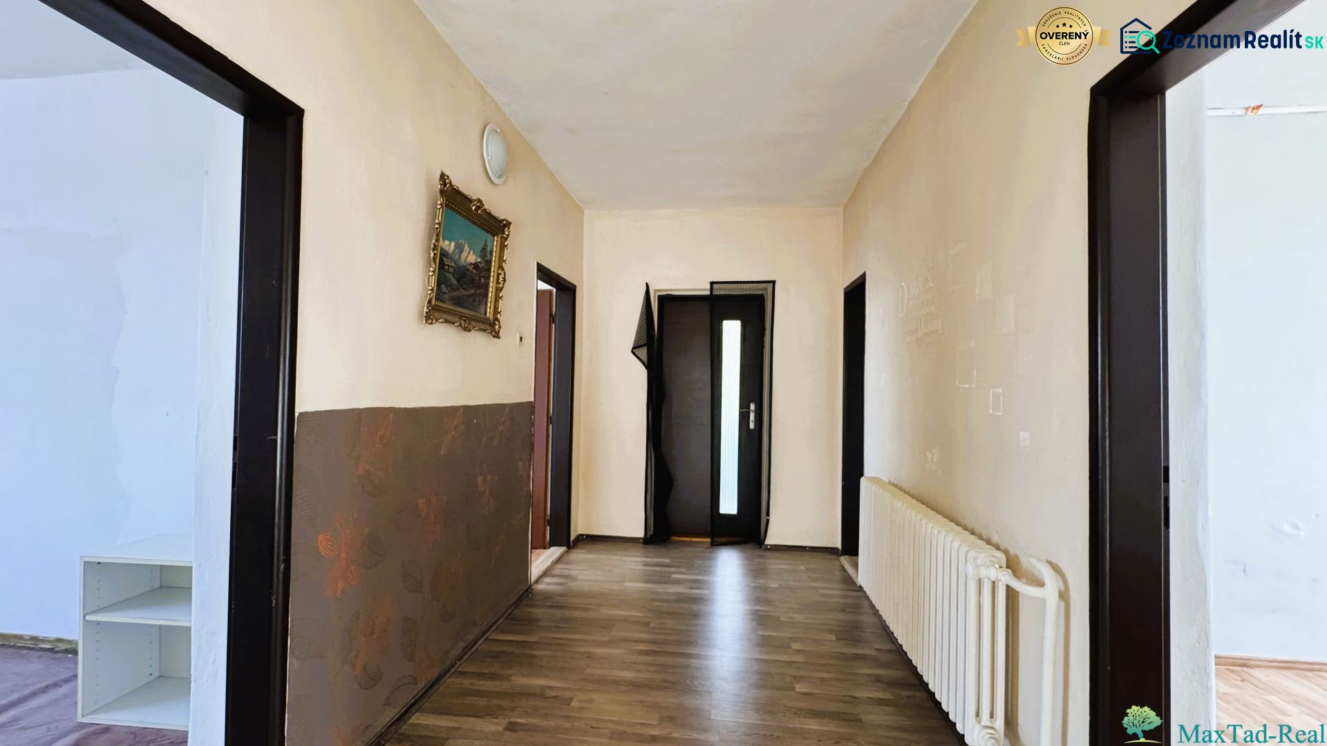 Ein Flur in einem Einfamilienhaus mit einem Holzboden und einem Bild an der Wand.