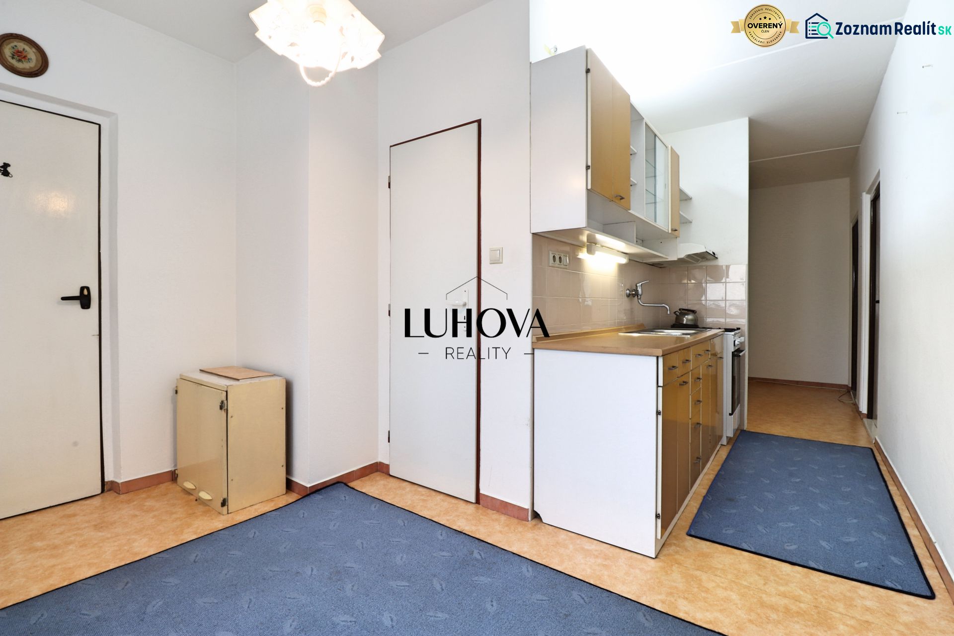Küche in einer 2-Zimmer-Wohnung mit Küchenzeile und blauen Teppichen auf dem Boden.
