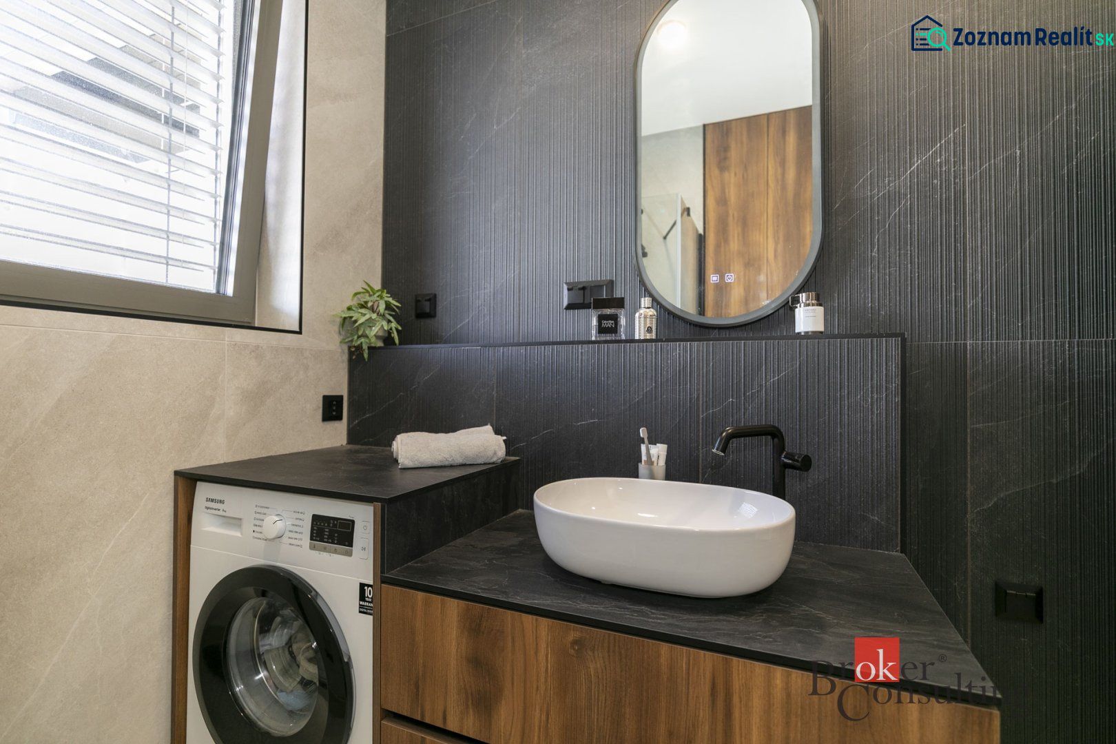 Badezimmer einer Zweizimmerwohnung mit Waschbecken, Waschmaschine und Spiegel.