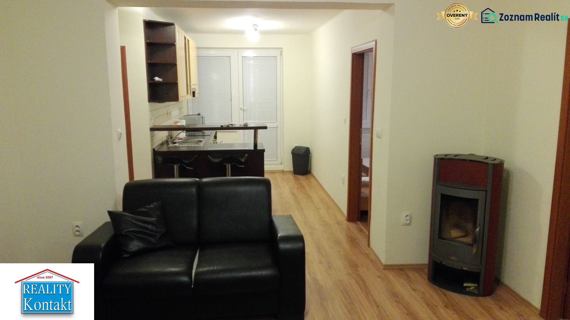 Wohnzimmer mit Ledersofa, Küchenzeile und Holzboden in einer 3-Zimmer-Wohnung.