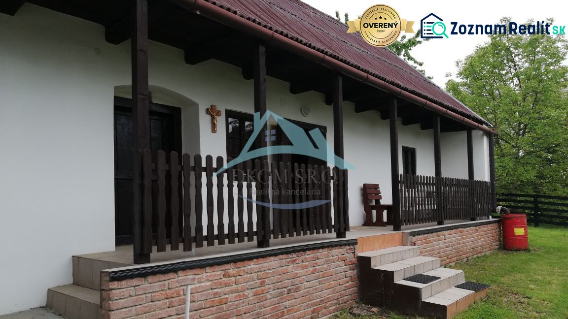 Ein Einfamilienhaus mit Terrasse, Holzzaun und Ziegelgrundlage in einer natürlichen Umgebung.