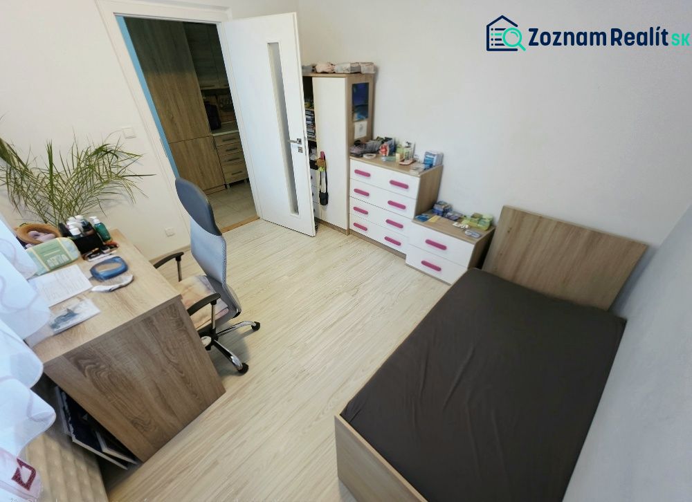 Ein Zimmer in einer 4-Zimmer-Wohnung mit Holzboden, Bett und Schreibtisch.