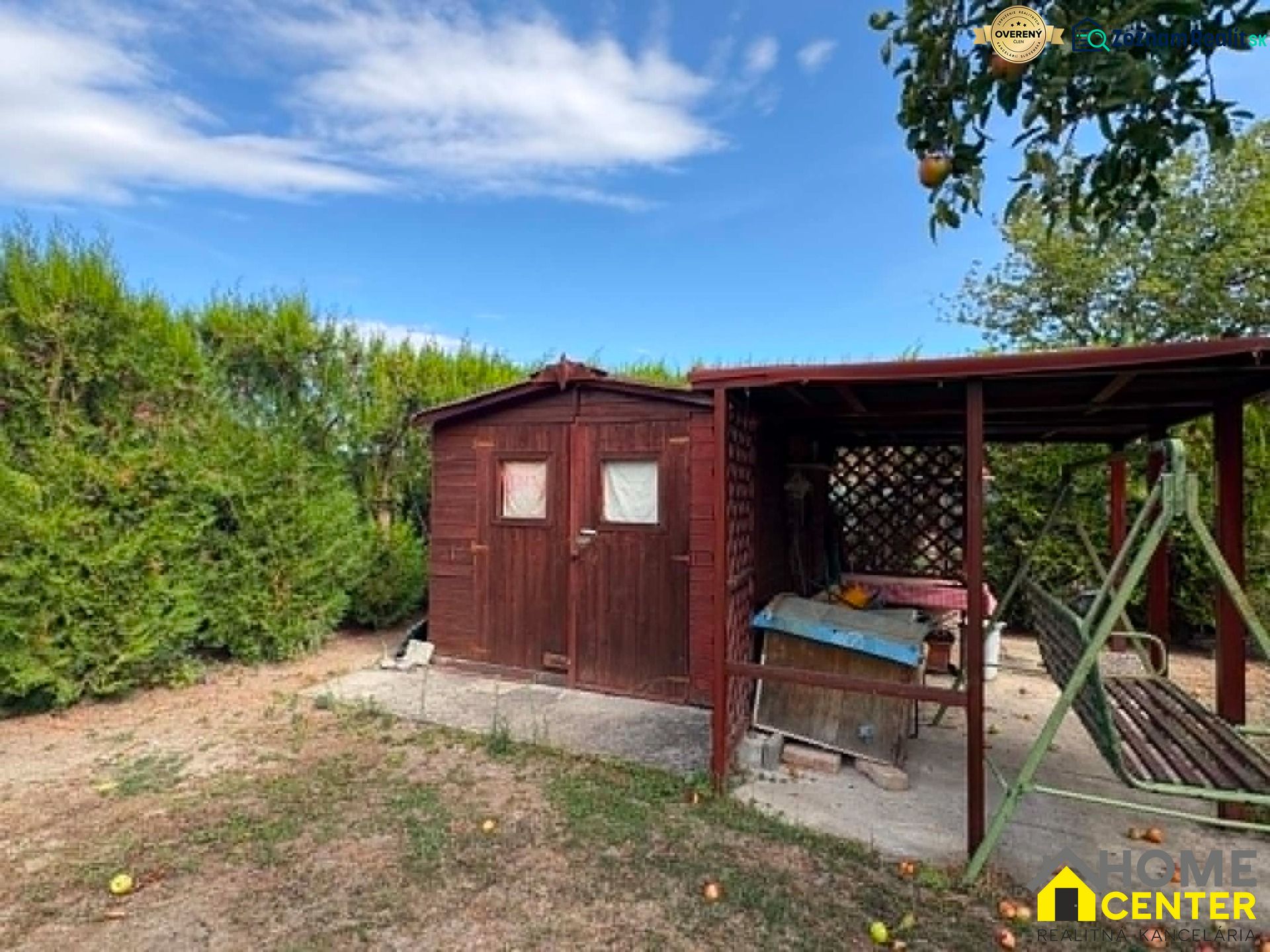 Ein hölzerner Pavillon und eine Schaukel im Garten in Komárno mit Obstbäumen.