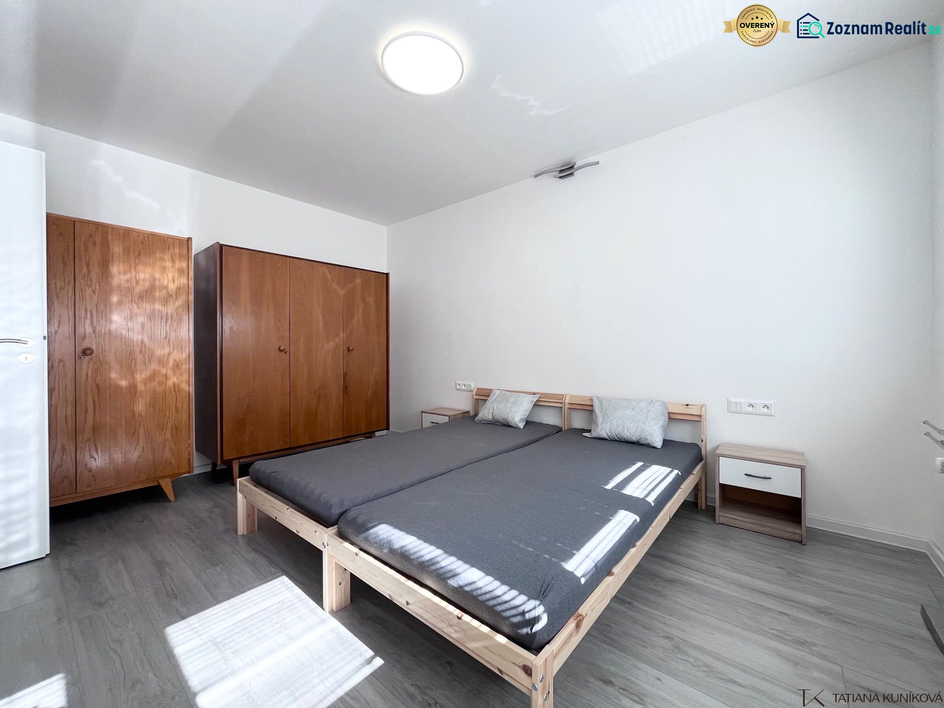 Schlafzimmer mit Bett, Holzschränken und Boden mit Holzdekor in einer 3-Zimmer-Wohnung.