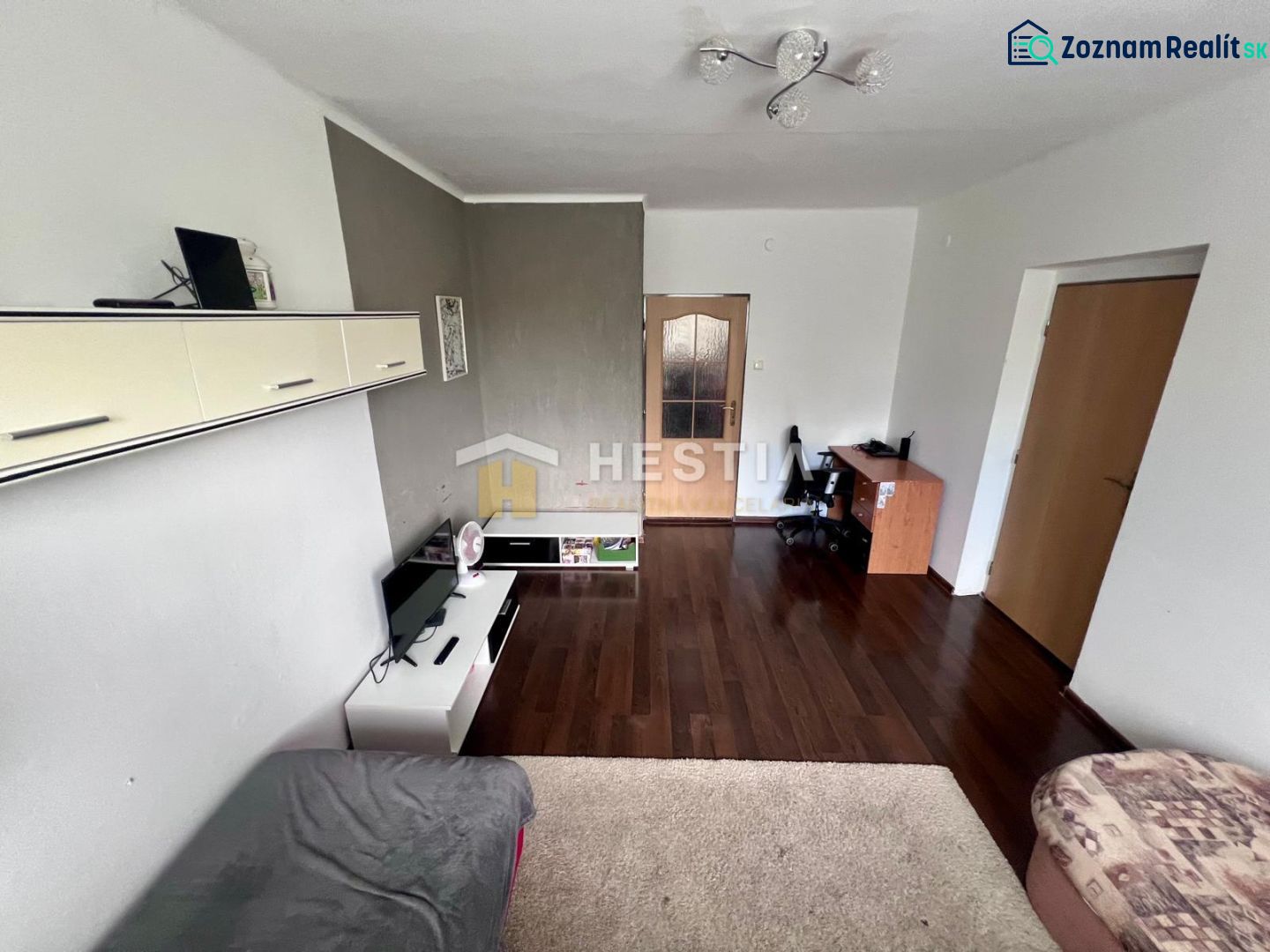 Wohnzimmer in einer Zweizimmerwohnung mit Holzboden und Möbeln.