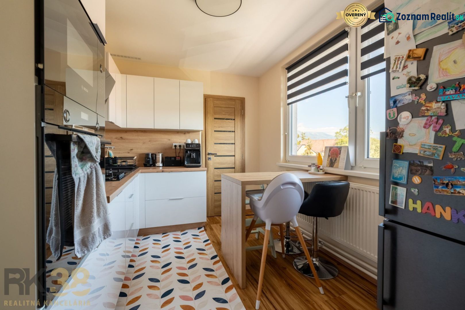 Küche in einer 3-Zimmer-Wohnung mit Holzdekor, weißen Möbeln und dekorativem Teppich.