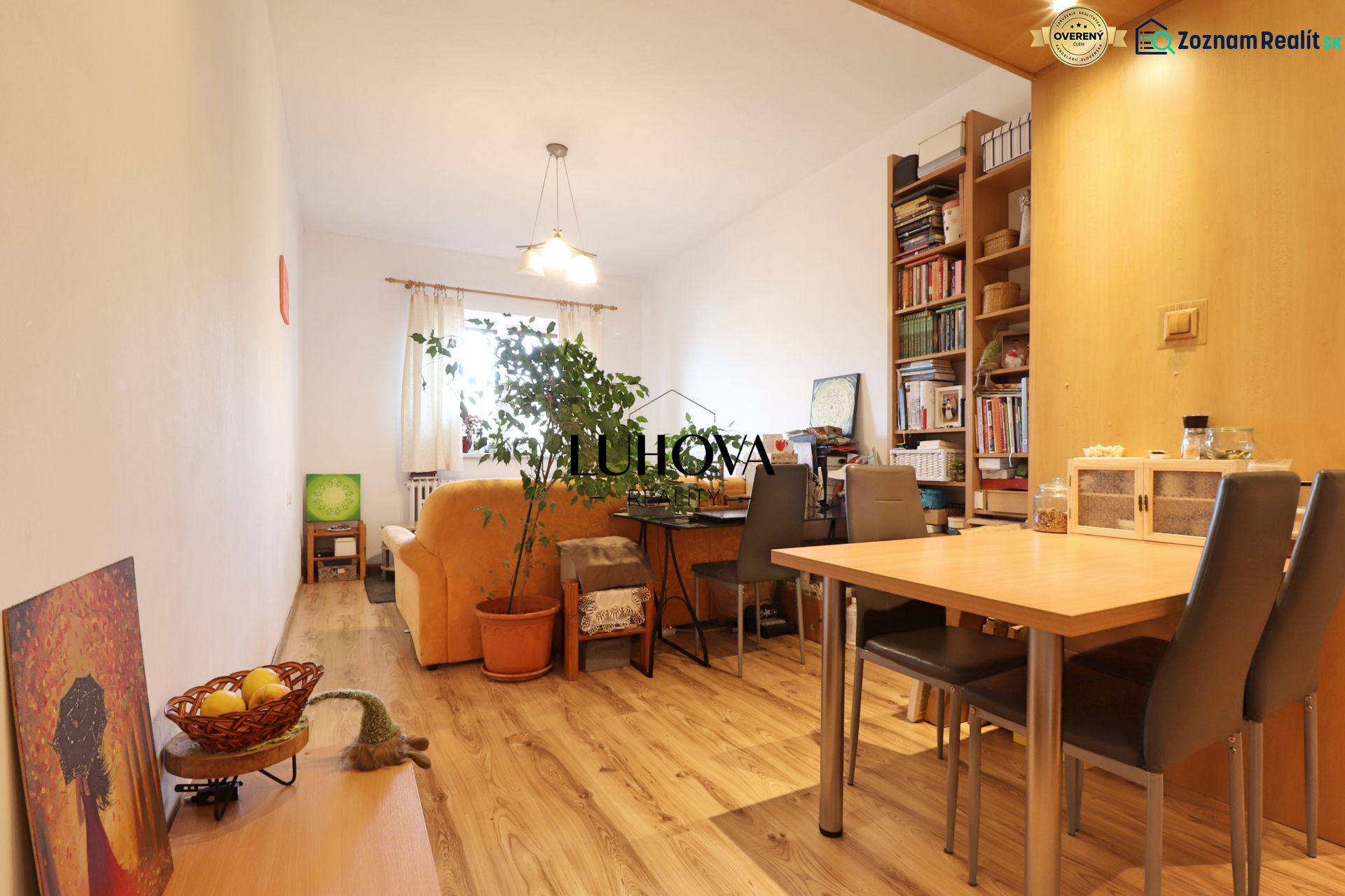 Wohnzimmer mit Holzdekorboden, Sofa, Tisch und Bücherregal in einer Zweizimmerwohnung.